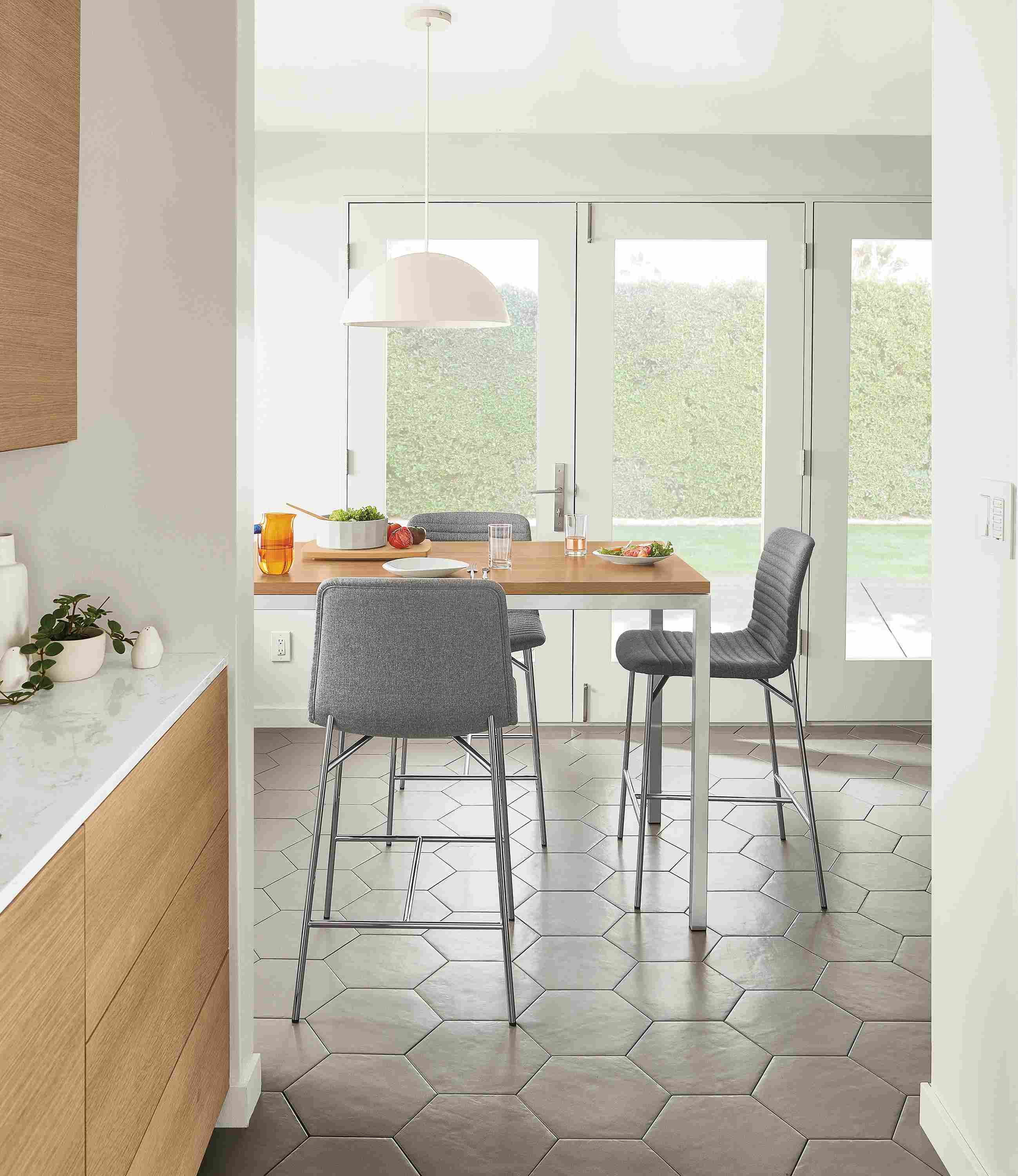 Dining area with 3 cato counter stools in medley grey and portica counter table in stainless with rye on red oak top.