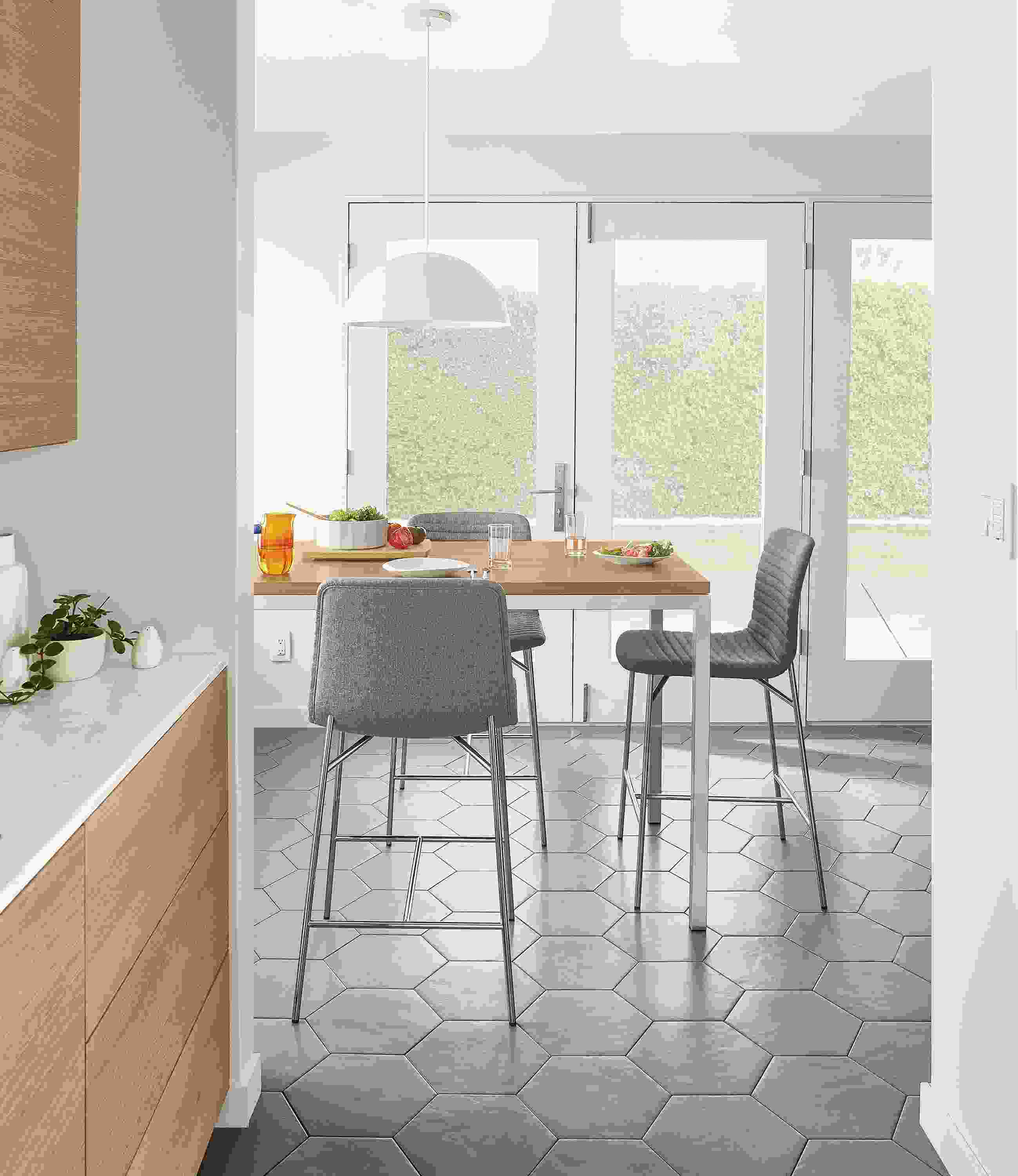 Dining area with 3 cato counter stools in medley grey and portica counter table in stainless with rye on red oak top.