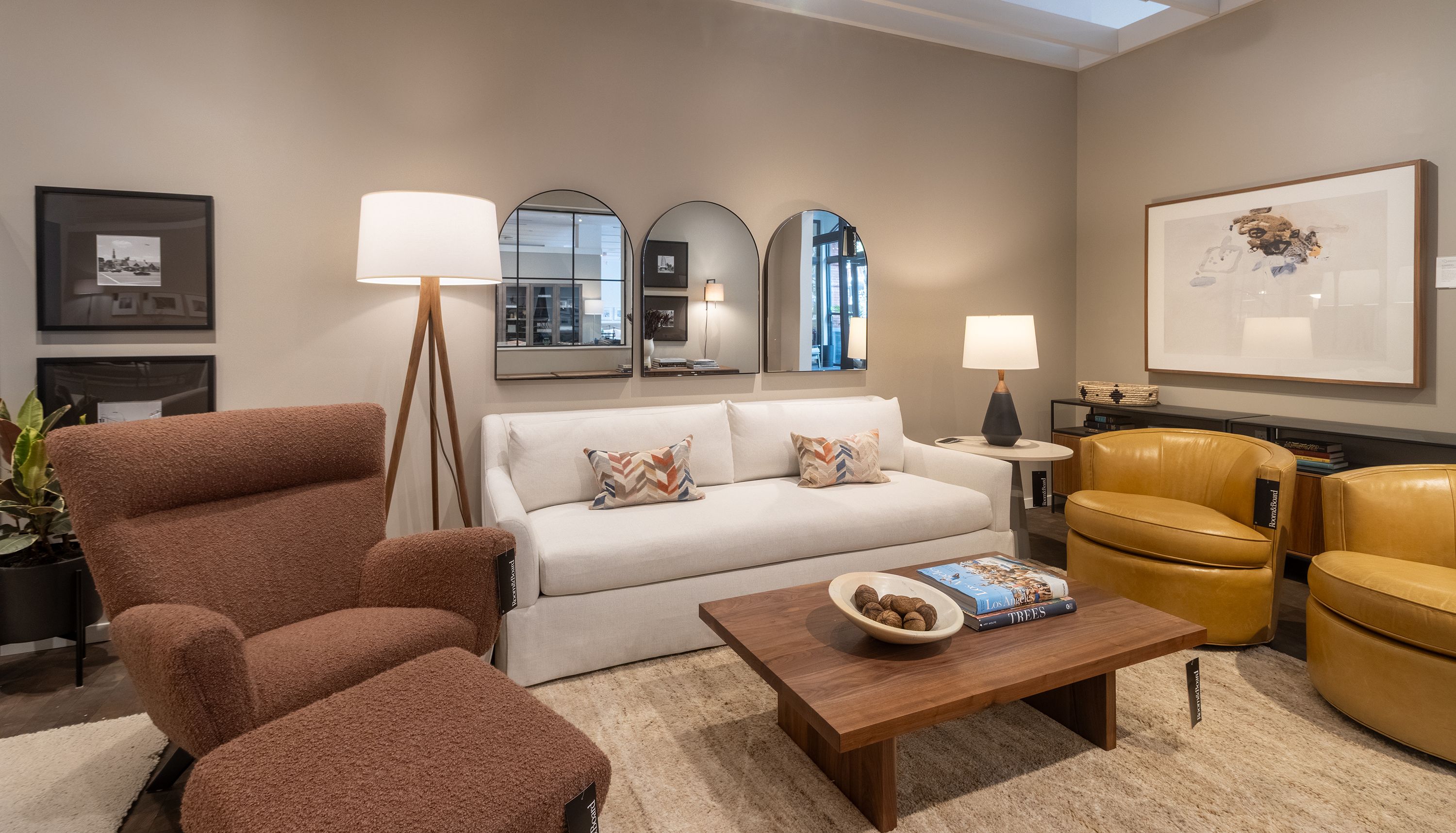 Store image with Sybil skirted bench cushion sofa in Sumner Ivory and 2 Otis swivel chairs in Vento Camel leather.