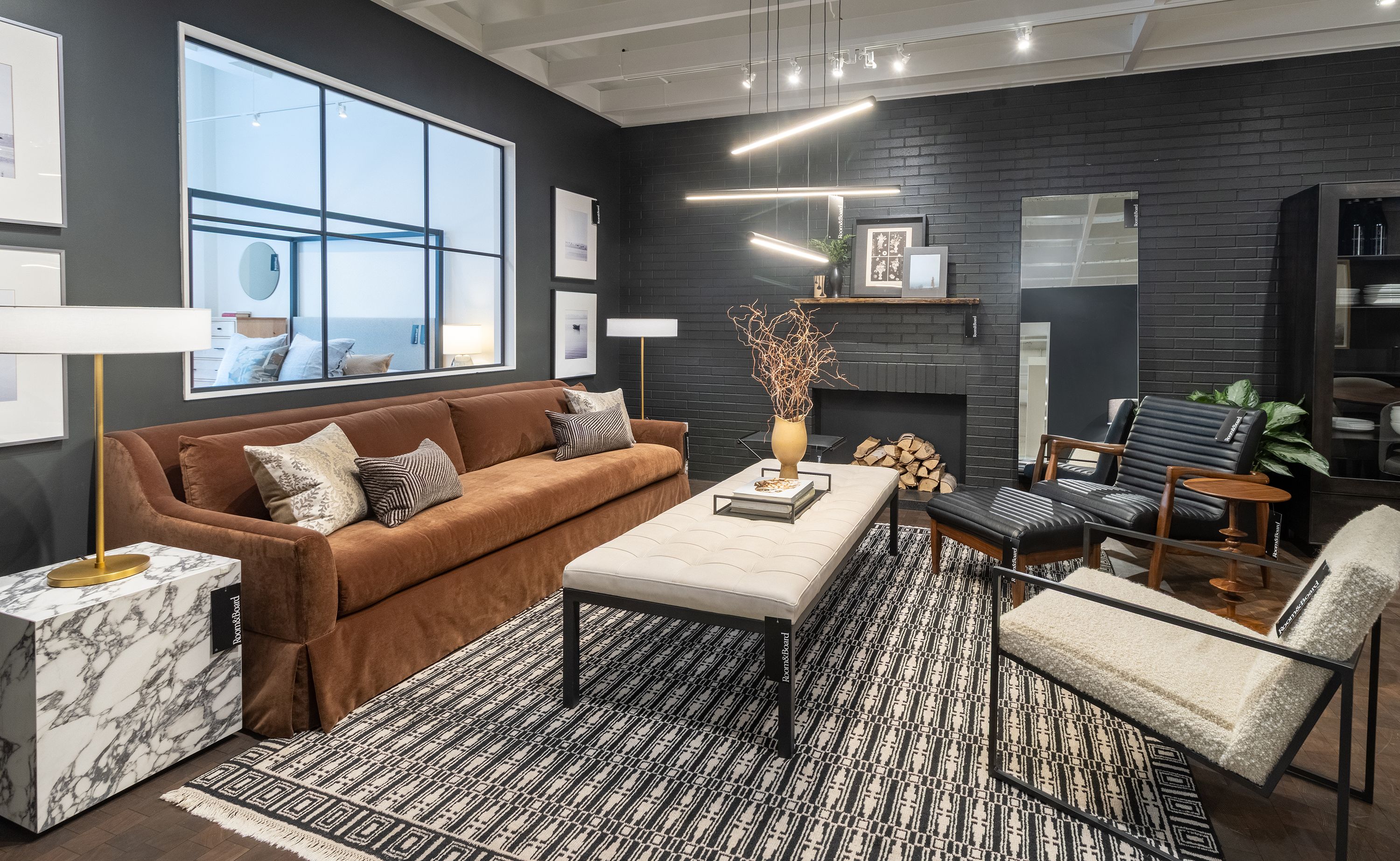 Store image with Sybil skirted sofa in Redding Nutmeg, Callan chair and ottoman in Pesaro Black leather and Tulum rug in ebony.