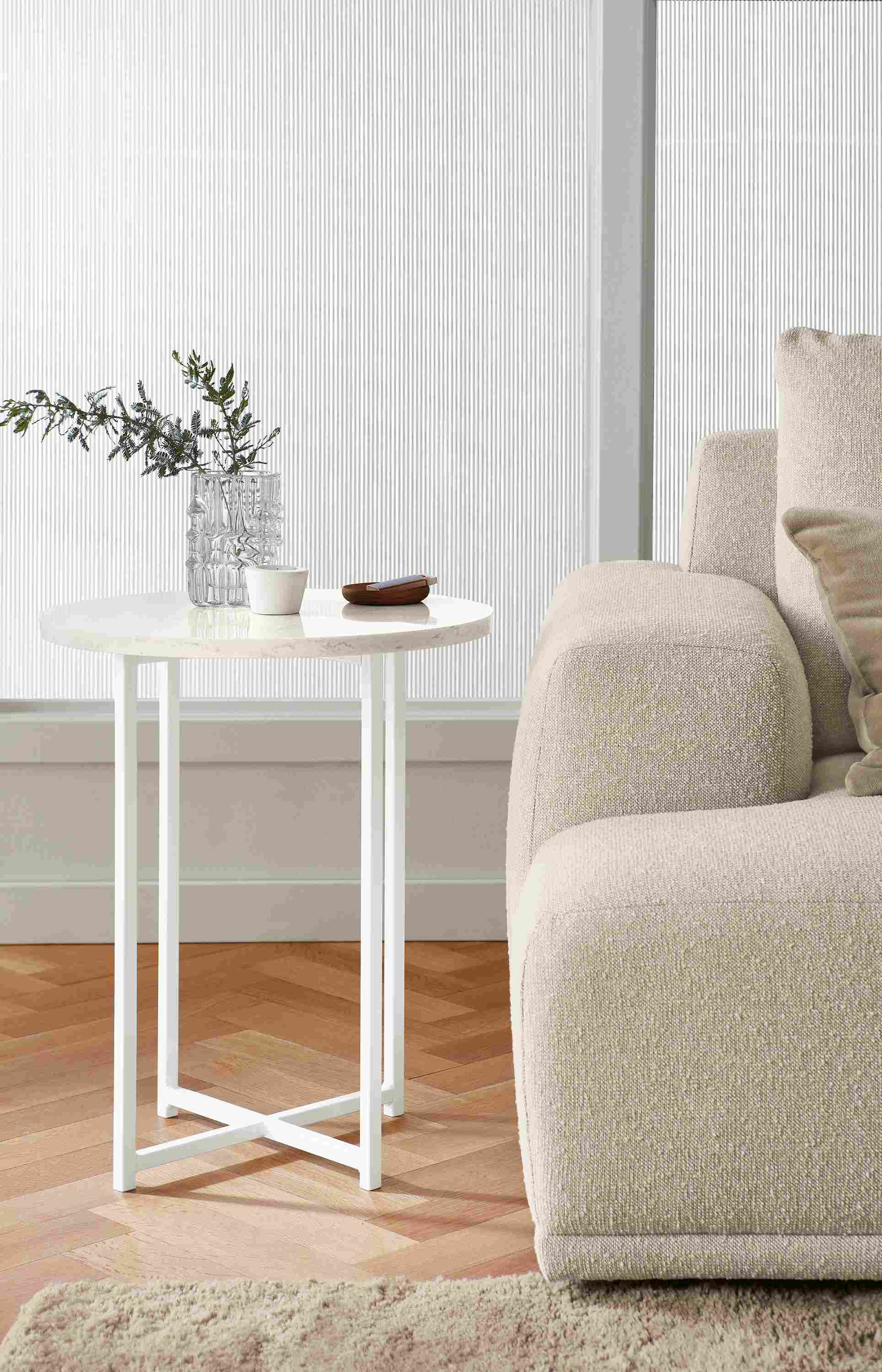 Living room setting of Classic 18-round end table in white with marbled white quartz top next to Fia Sofa.