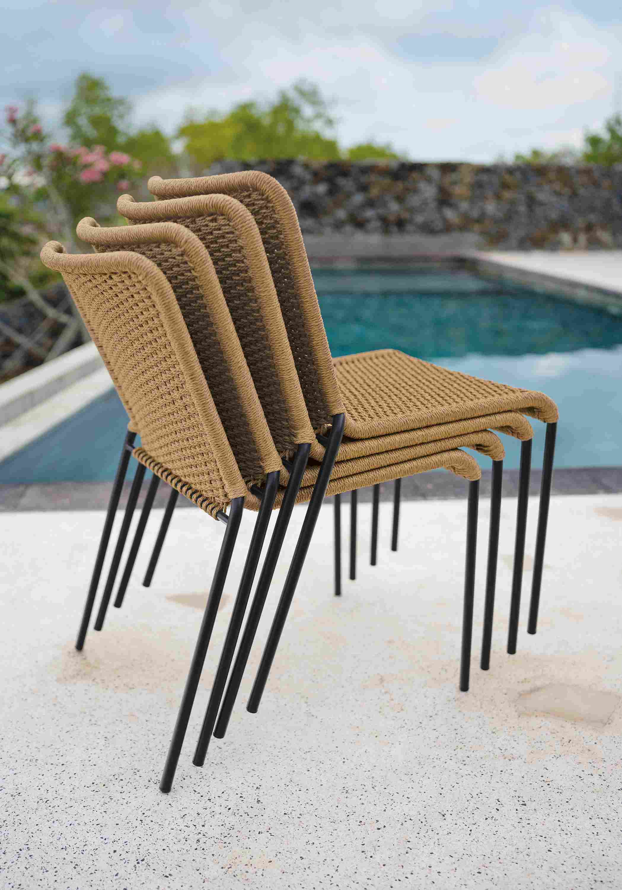 Stack of four Clea Outdoor Side Chairs in Natural cording with black legs.