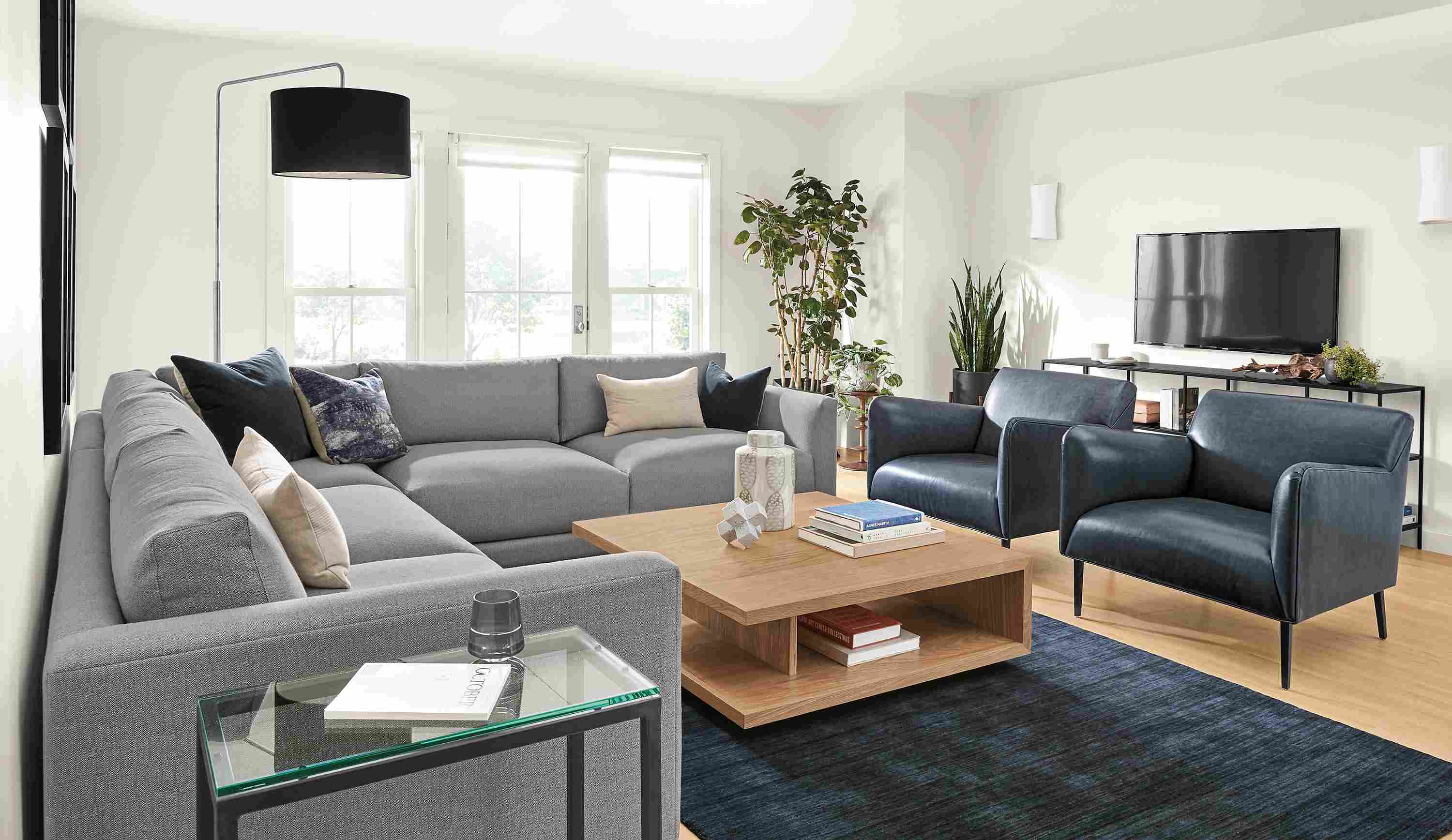 Living room with clemens 3-piece sectional in hines fabric, 2 matteo chairs in vento ink leather and nomad rug in indigo.