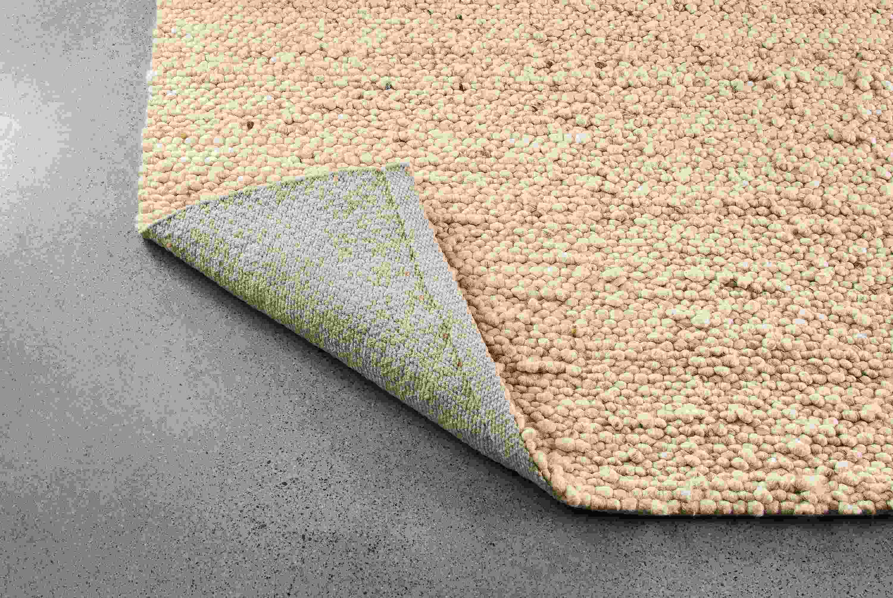 Cobble 8 by 10 rug in ecru shown with corner flipped up to show underside of rug.