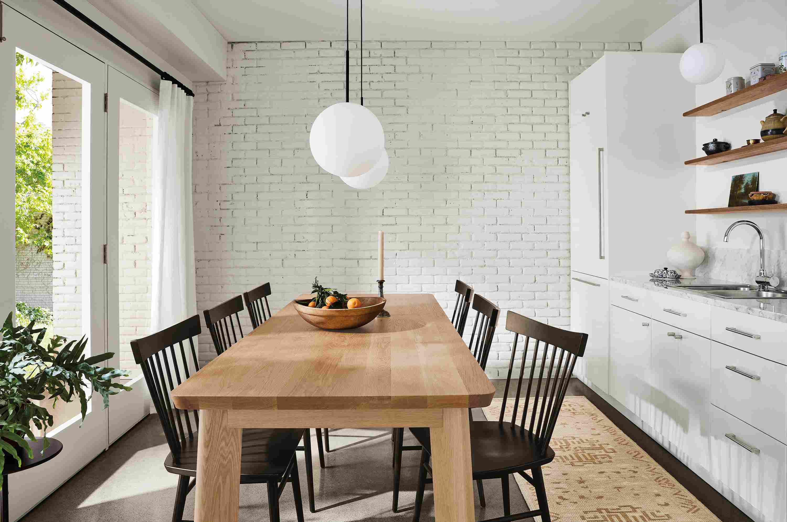 Dining area with colby table in rye on red oak, thatcher side chairs in charcoal, orbit white glass pendants.