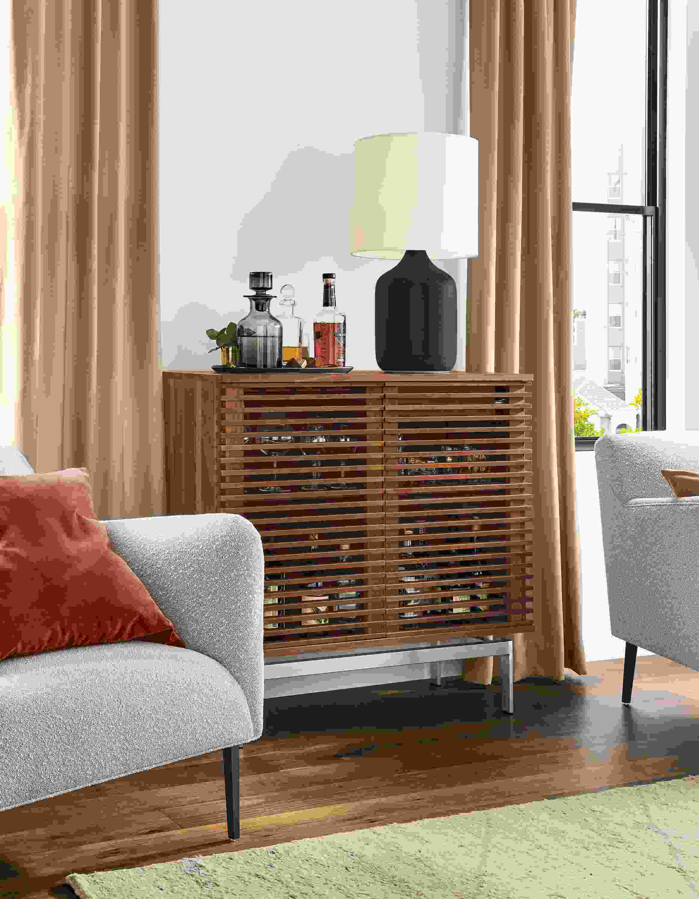 Detail of Coles two-door bar cabinet in walnut with stainless steel base in living room.