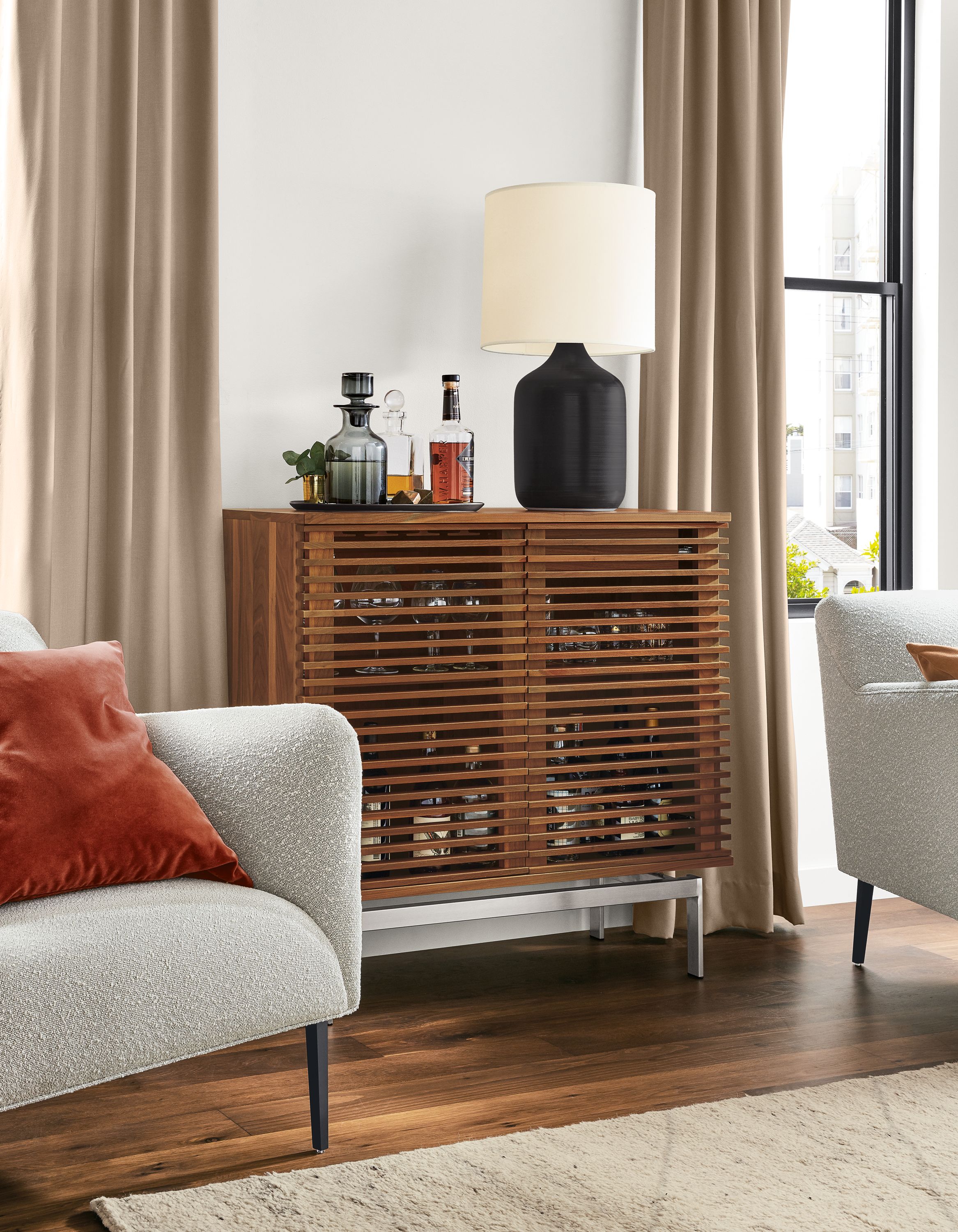 Detail of Coles two-door bar cabinet in walnut with stainless steel base in living room.