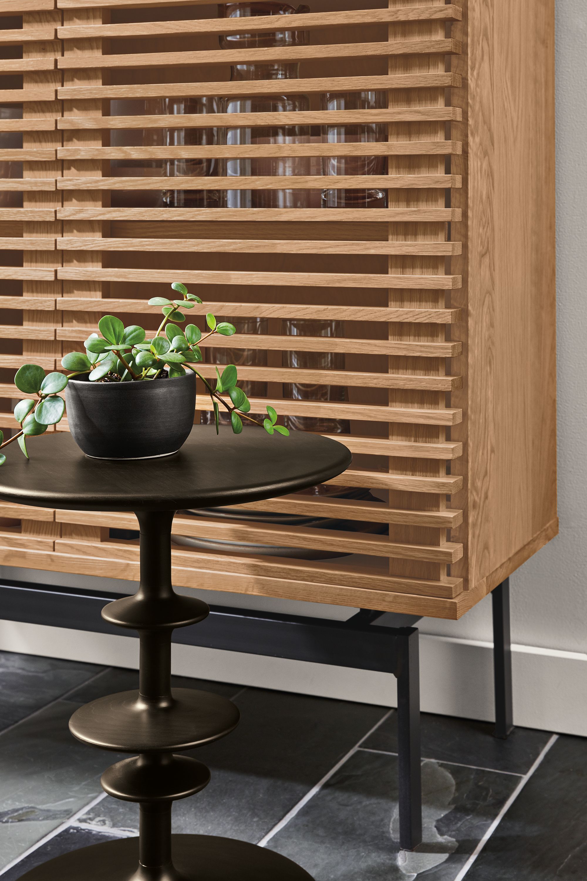 Close up of Coles 36-wide 60-high Two-Door Storage Cabinet in Rye along with Parks end table in charcoal.