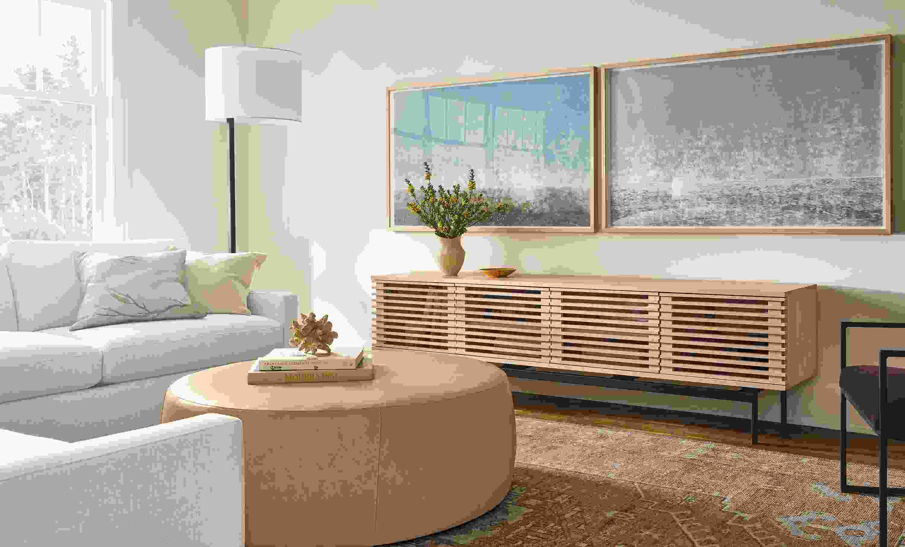 Living room with Coles 84-wide Media Cabinet in salt on red oak and Lind 42-diameter ottoman in Fiero Camel leather.