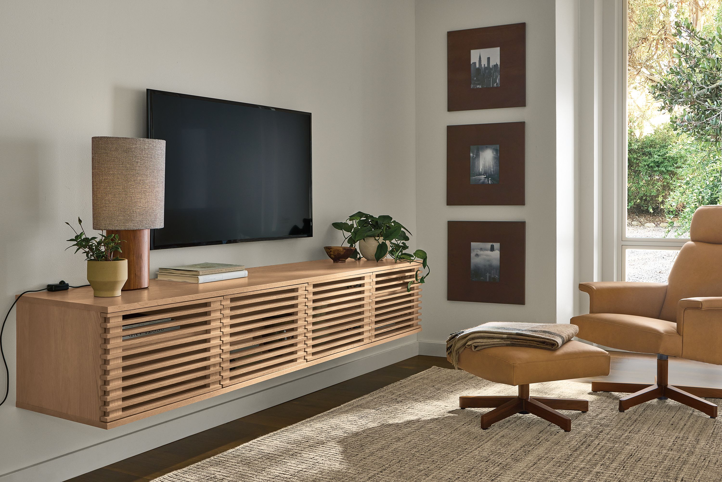 Living room with Coles 84-wide floating media cabinet in rye on red oak and Daniels chair and ottoman in Laino Camel leather.