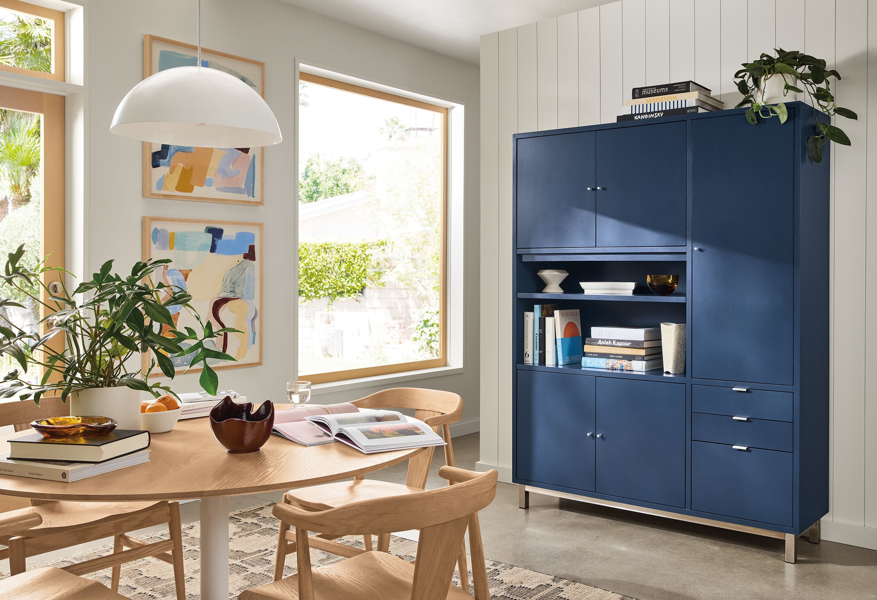 Dining area with Copenhagen custom cabinet in Navy, Aria round table and Evan arm chairs in rye on red oak.