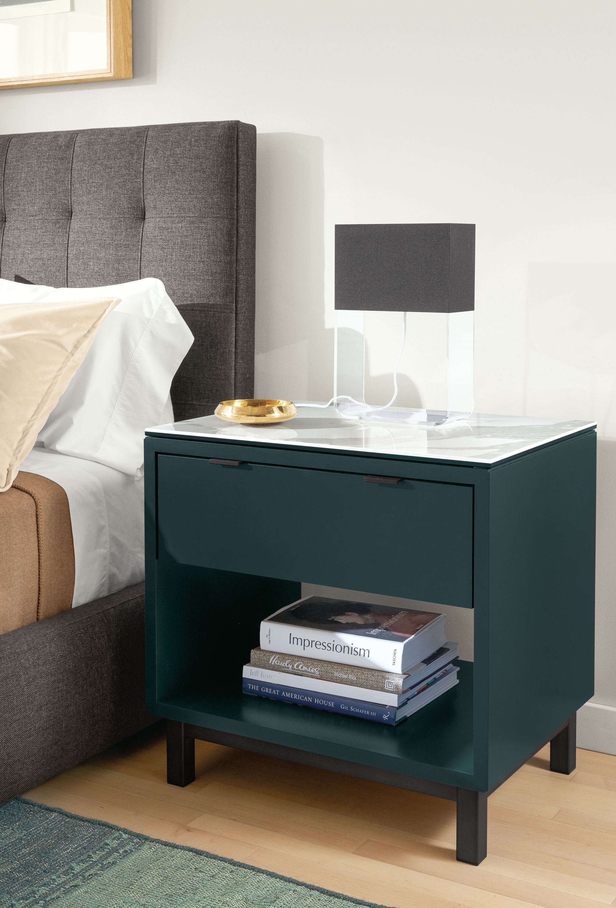 Close-up of Copenhagen nightstand in Slate with marbled white ceramic top beside bed.