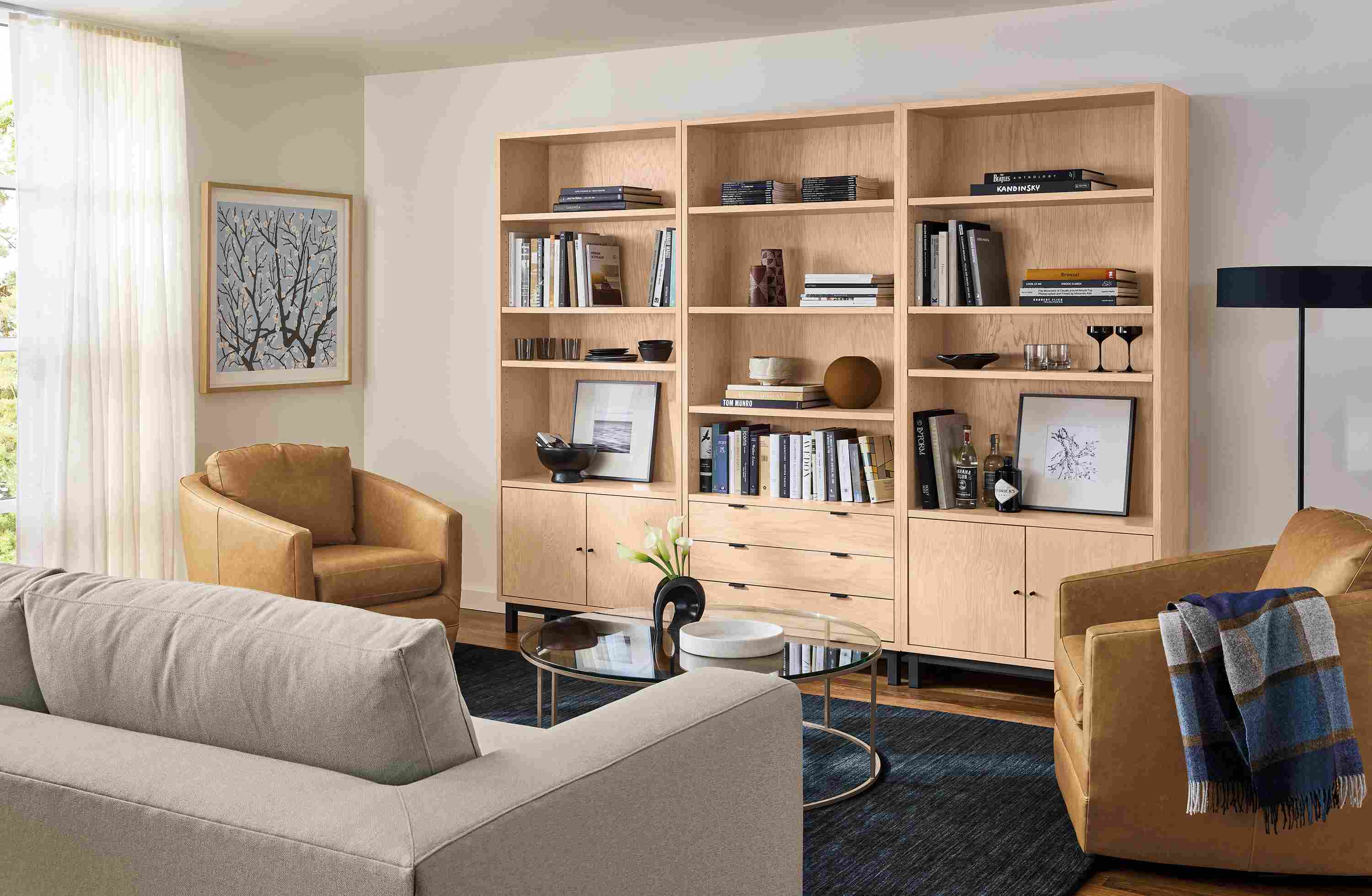 Living room the 3 copenhagen bookcases in salt on red oak and nomad 8 by 10 rug in black.