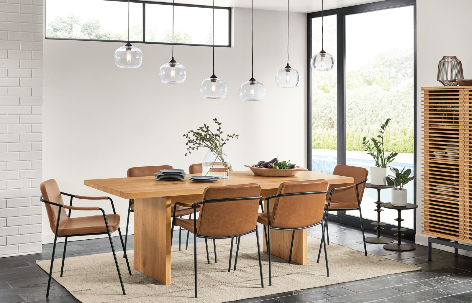Detail of Corbett dining table in white oak in large dining room with leather chairs.