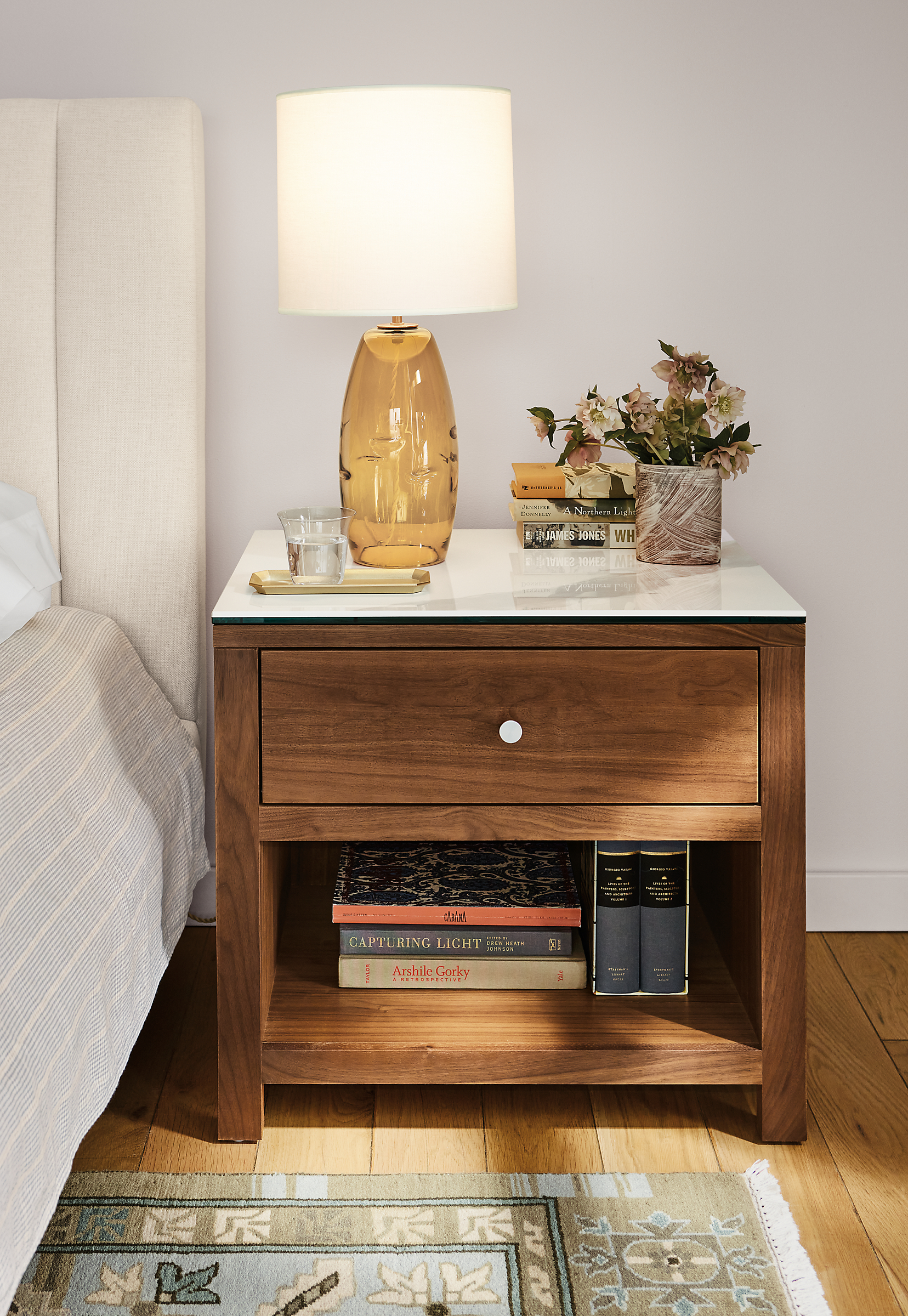 Bedroom with closeup of Corwin 26-wide nightstand in walnut with Marbled white ceramic top and Grace table lamp.