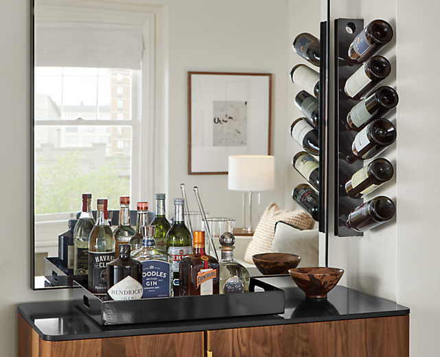 detail of black wine rack mounted on wall and black steel tray holding drink ingredients