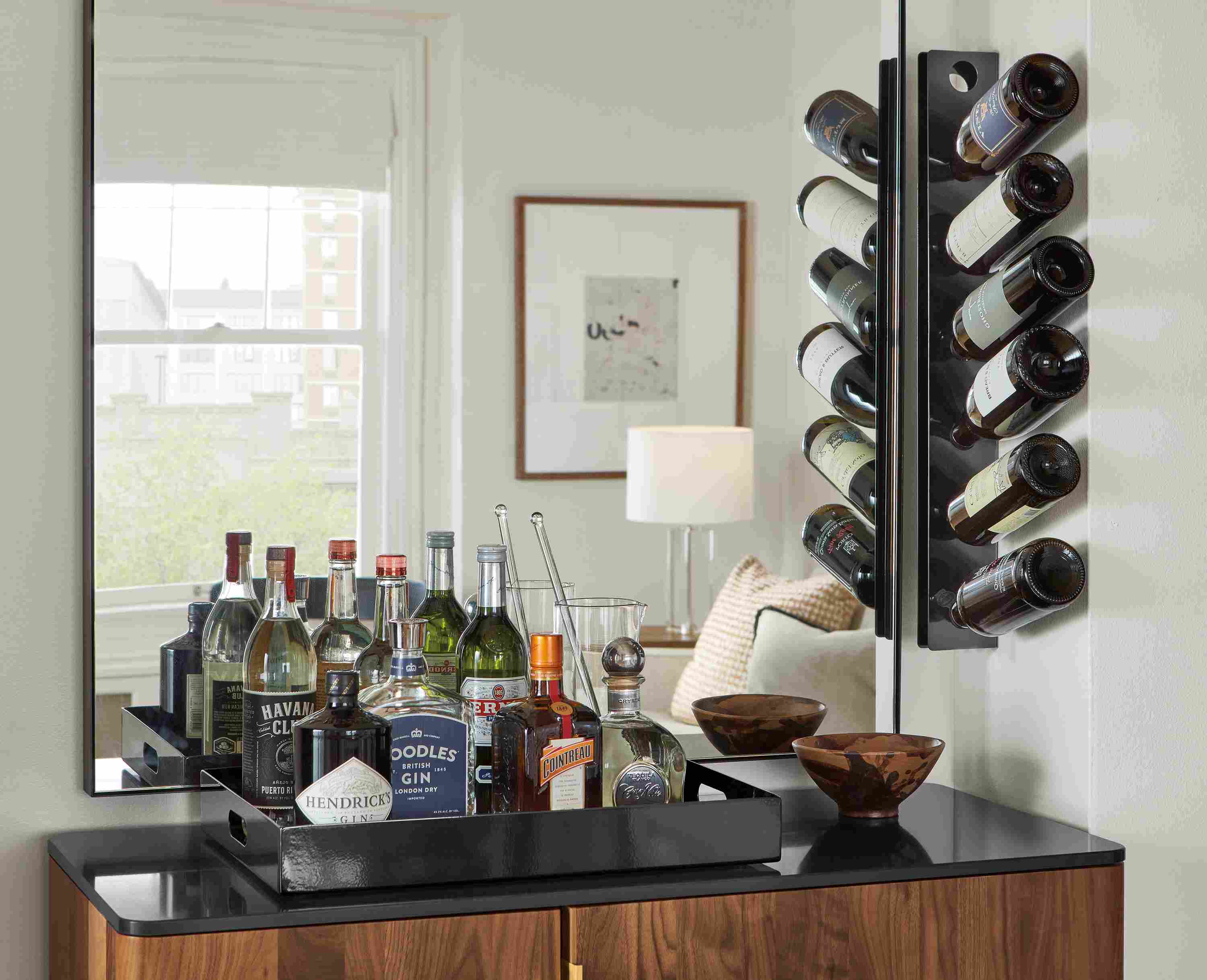 Detail of black wine rack mounted on wall and black steel tray holding drink ingredients.