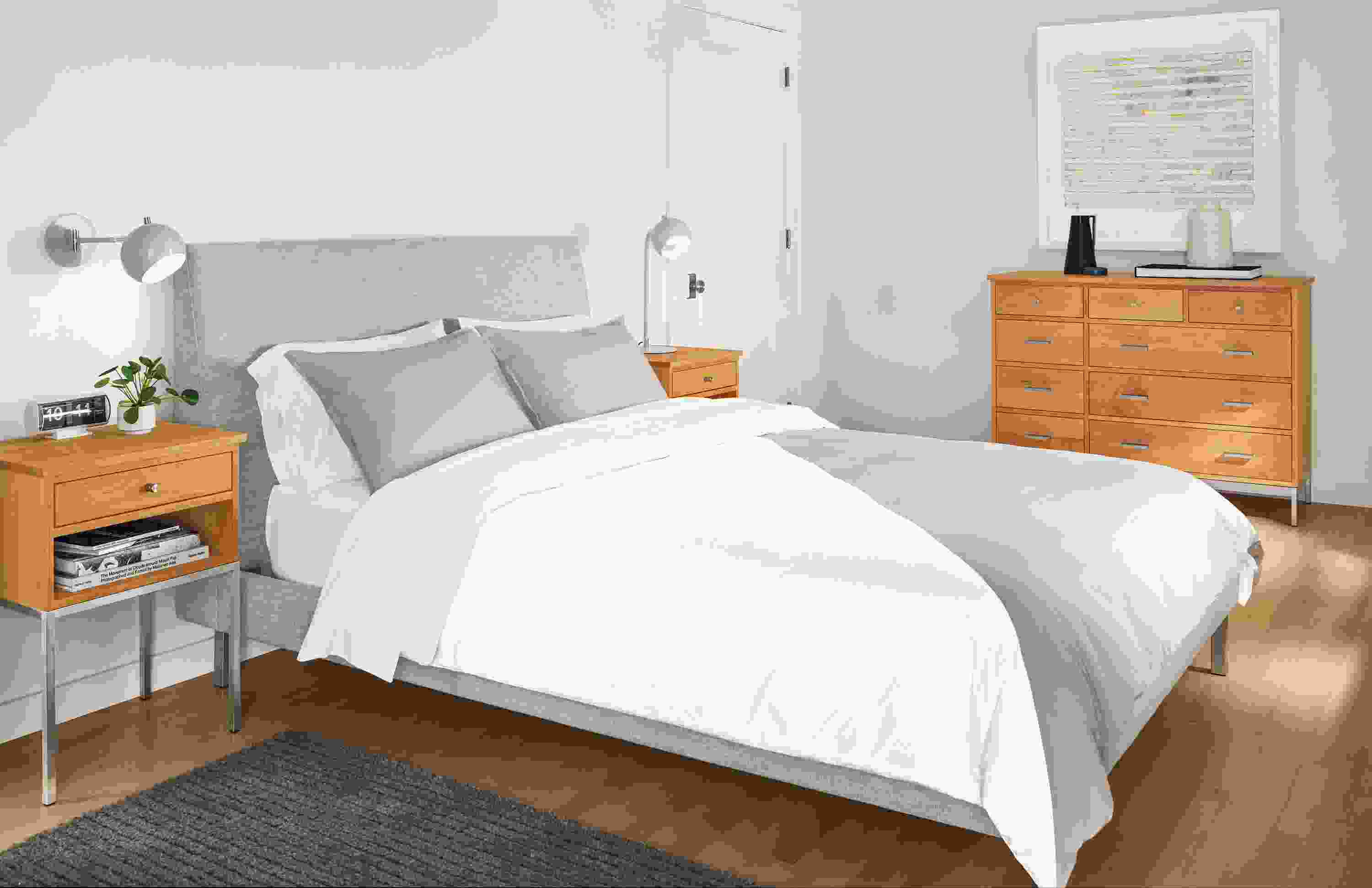 Detail of Crossway duvet cover in natural-grey with Camber wall sconce and table lamp in grey, and Linear nightstands in cherry.