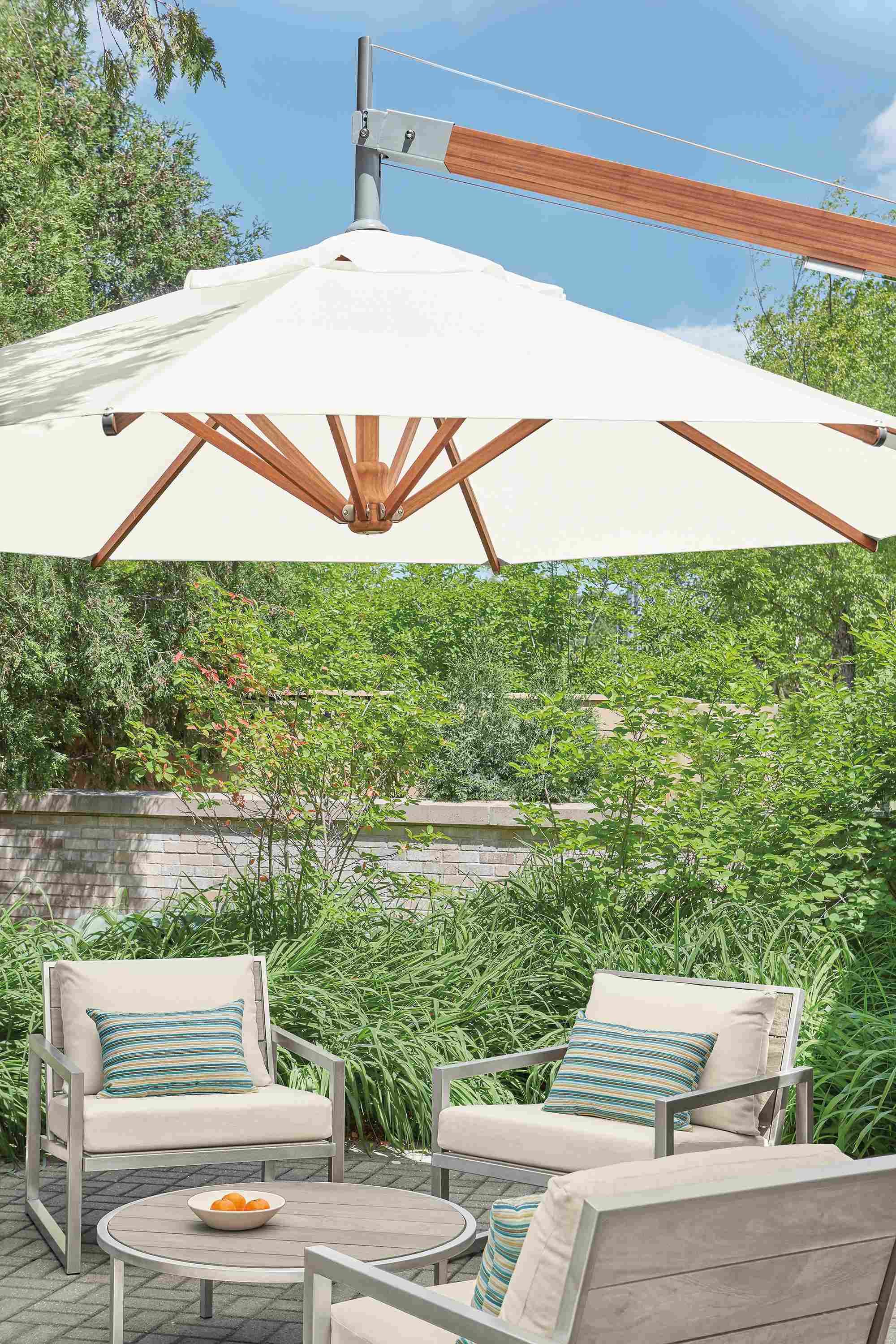 Cumulo patio umbrella above Montego lounge chairs and Montego coffee table in aged ash.
