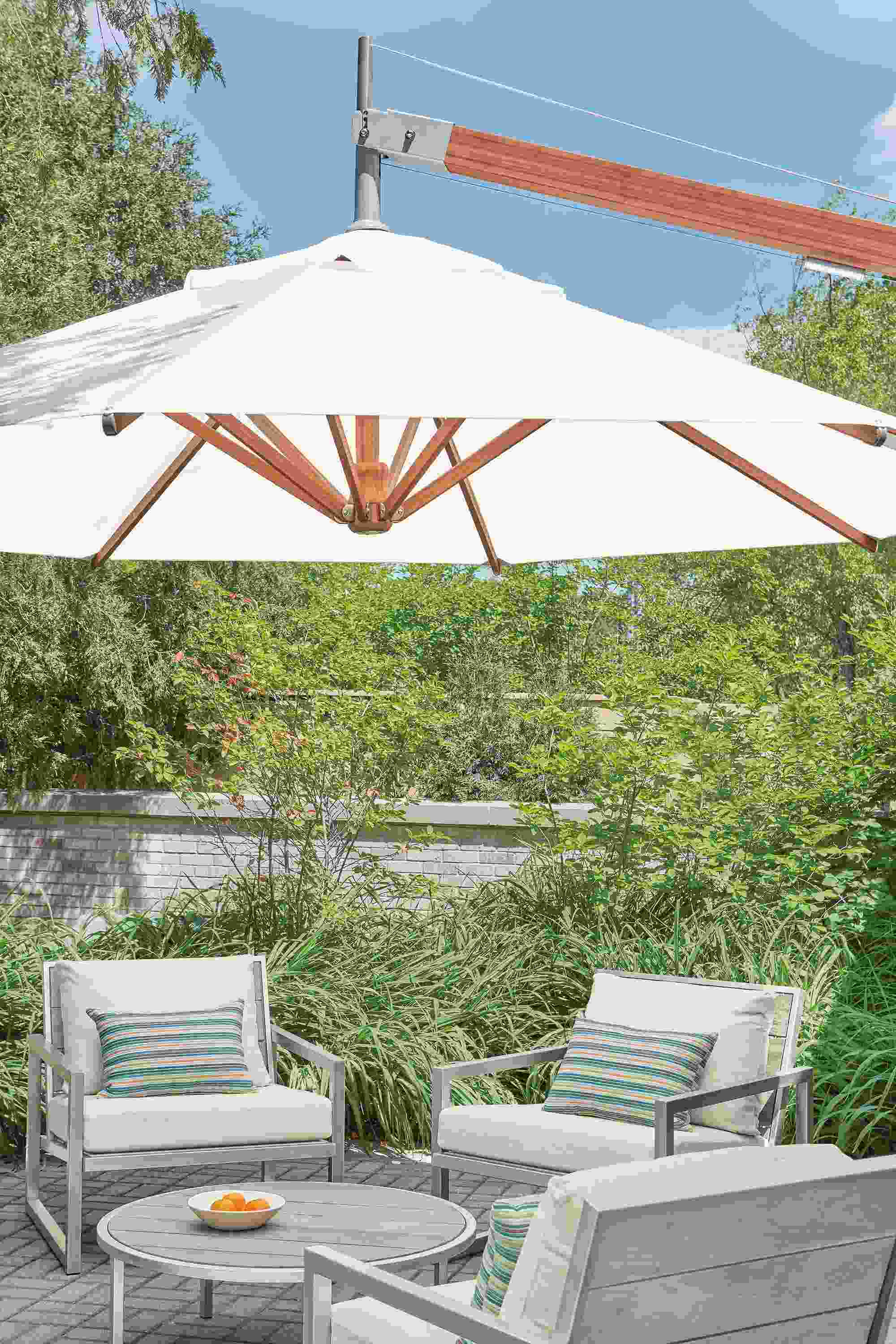 Cumulo patio umbrella above Montego lounge chairs and Montego coffee table in aged ash.