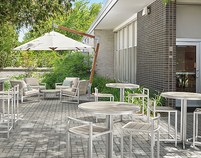 outdoor dining area with cumulo patio umbrella, montego chairs, tables, stools and bar  in aged ash.