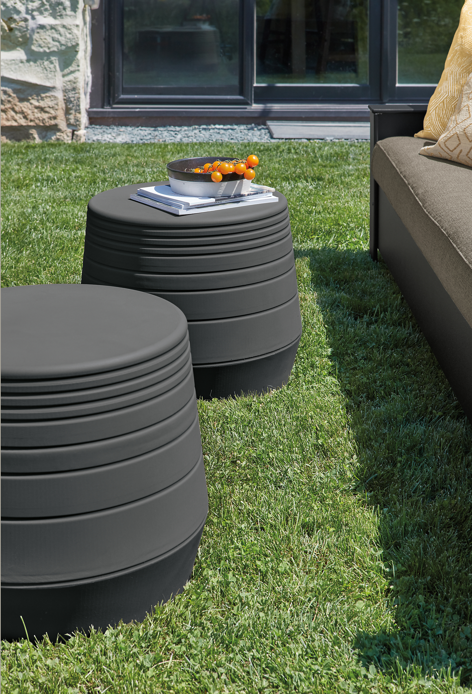 Two Cusp 21-round stools in grey in outdoor setting.