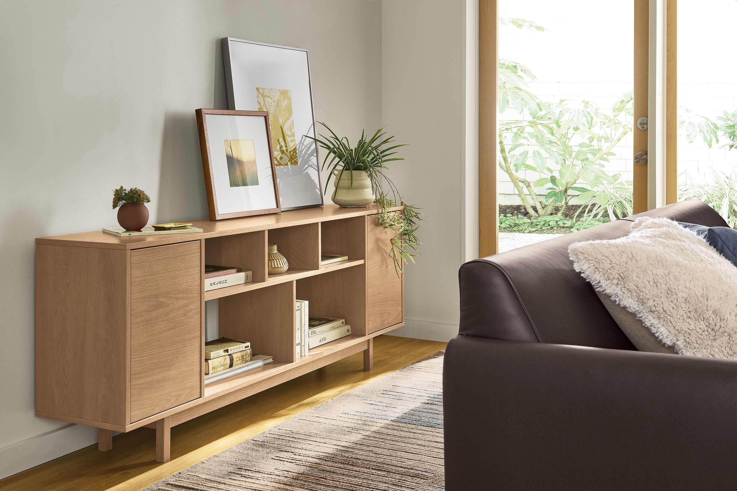 Living room with Dahl 72-wide 2-door console bookcase in rye on red oak and vienna sofa in pesaro espresso leather.