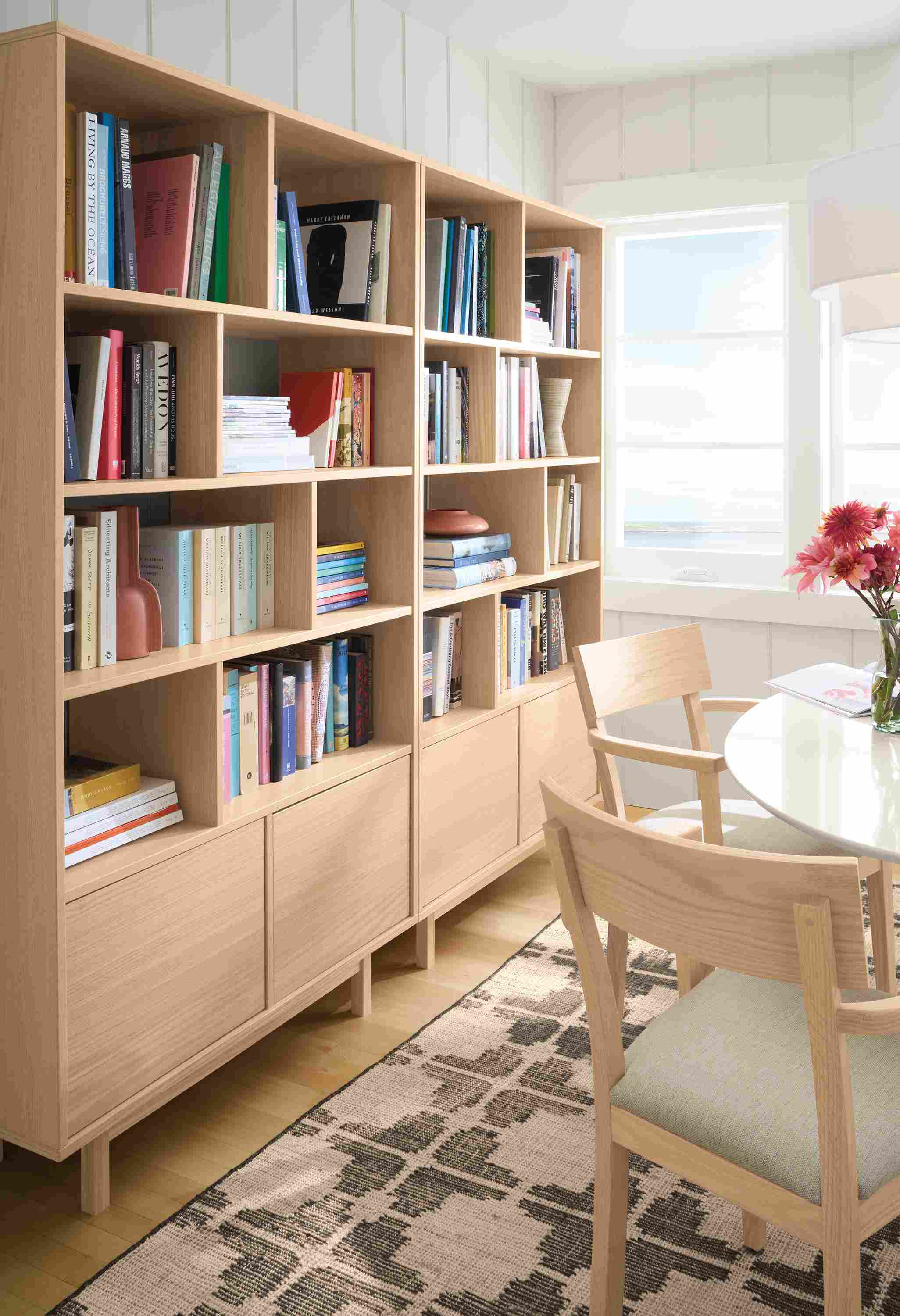 Sunny dining nook with detail of 2 Dahl 42-wide, 2-door bookcases in salt on red oak.