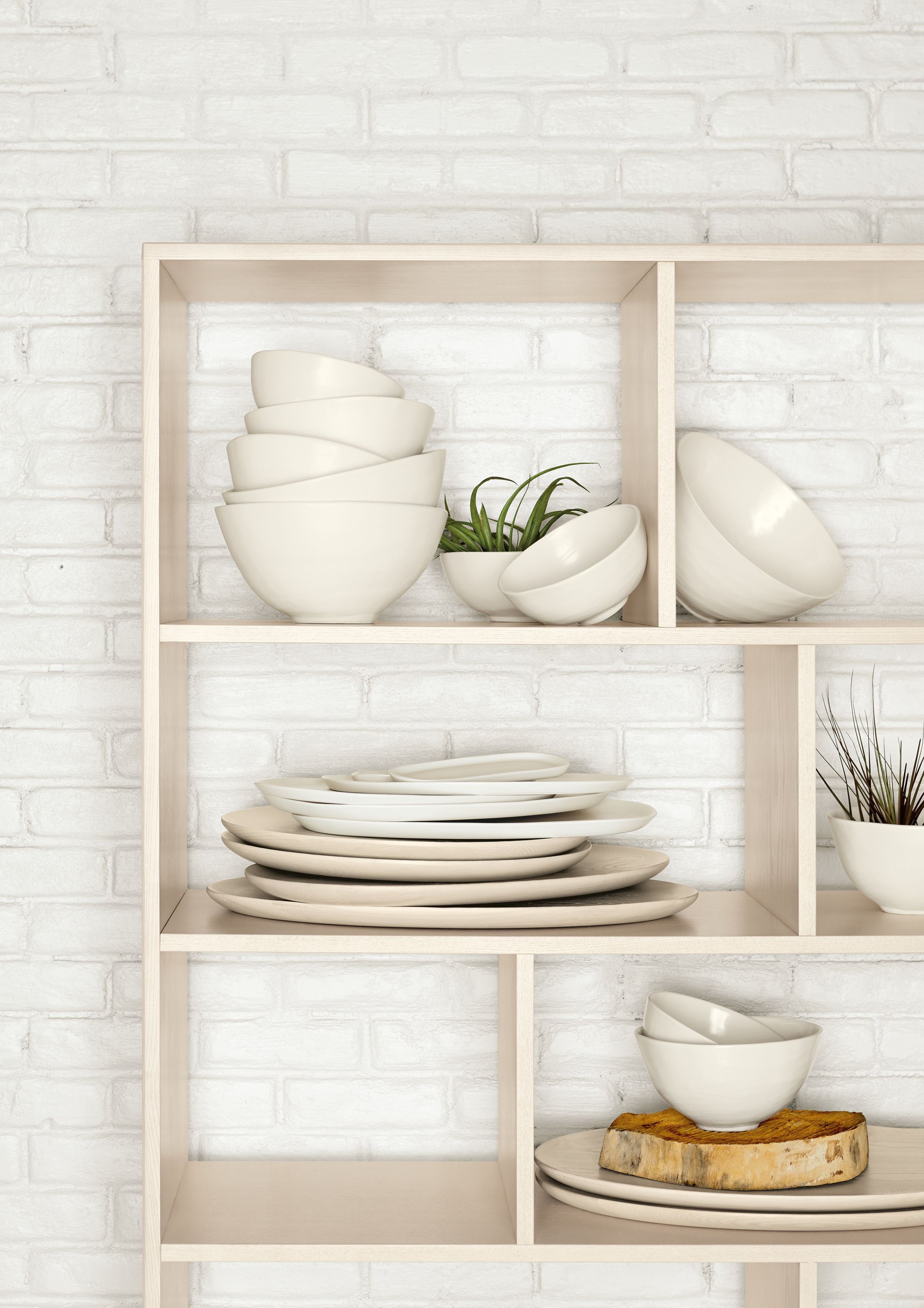 Detail of Dahl bookcase against white brick wall.