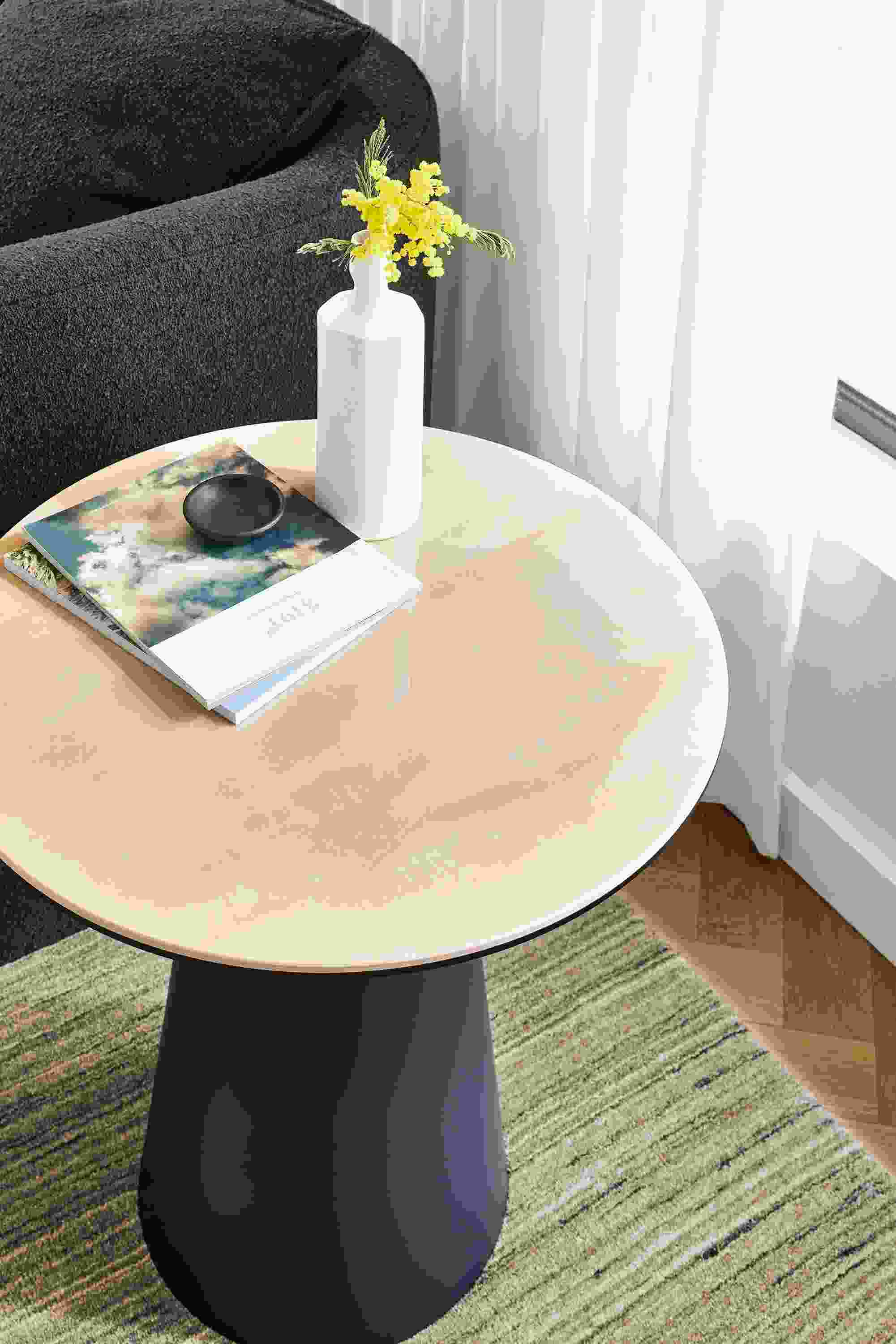 Detail of Decker 22-round end table in graphite with Marbled ecru ceramic top and Nomad rug in ivory and grey.