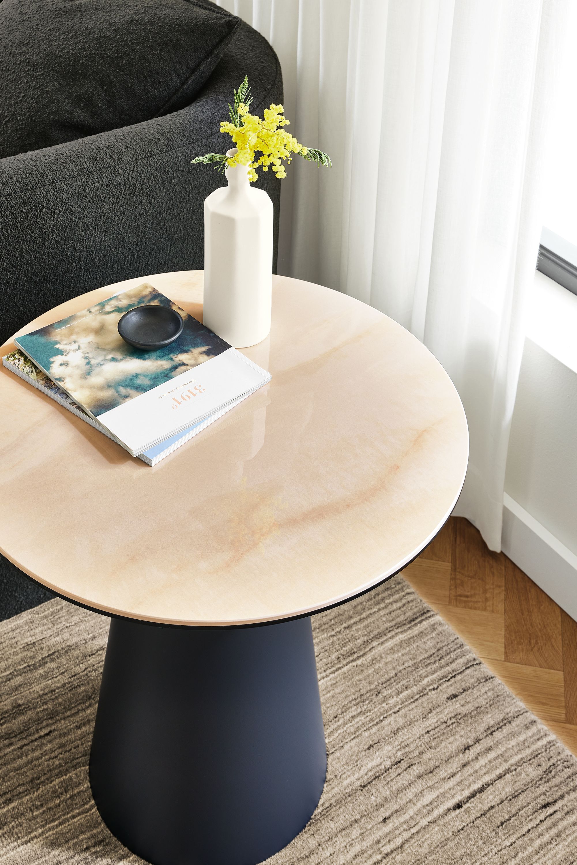 Detail of Decker 22-round end table in graphite with Marbled ecru ceramic top and Nomad rug in ivory and grey.