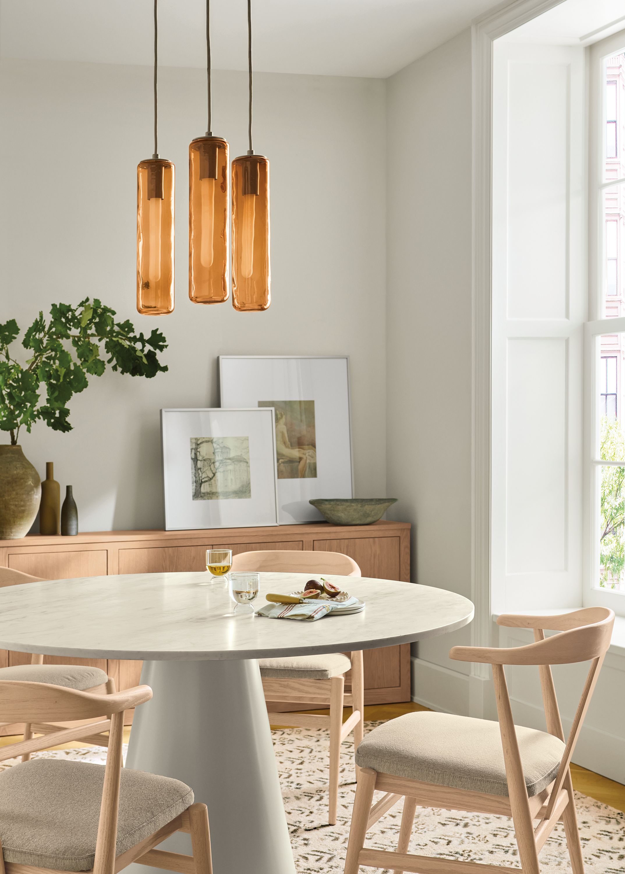 Dining room with Decker round table in marbled warm white quartz and taupe and 4 Evan arm chairs in Myers Taupe.