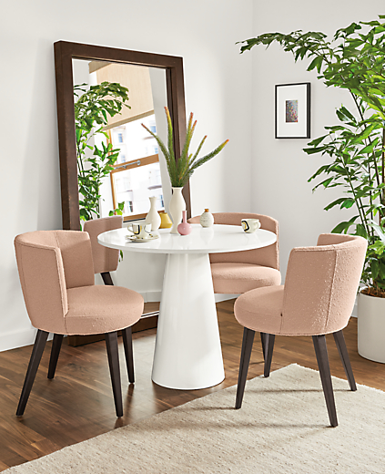 Detail of Decker round table with white quartz top and white base in dining room with pink chairs.