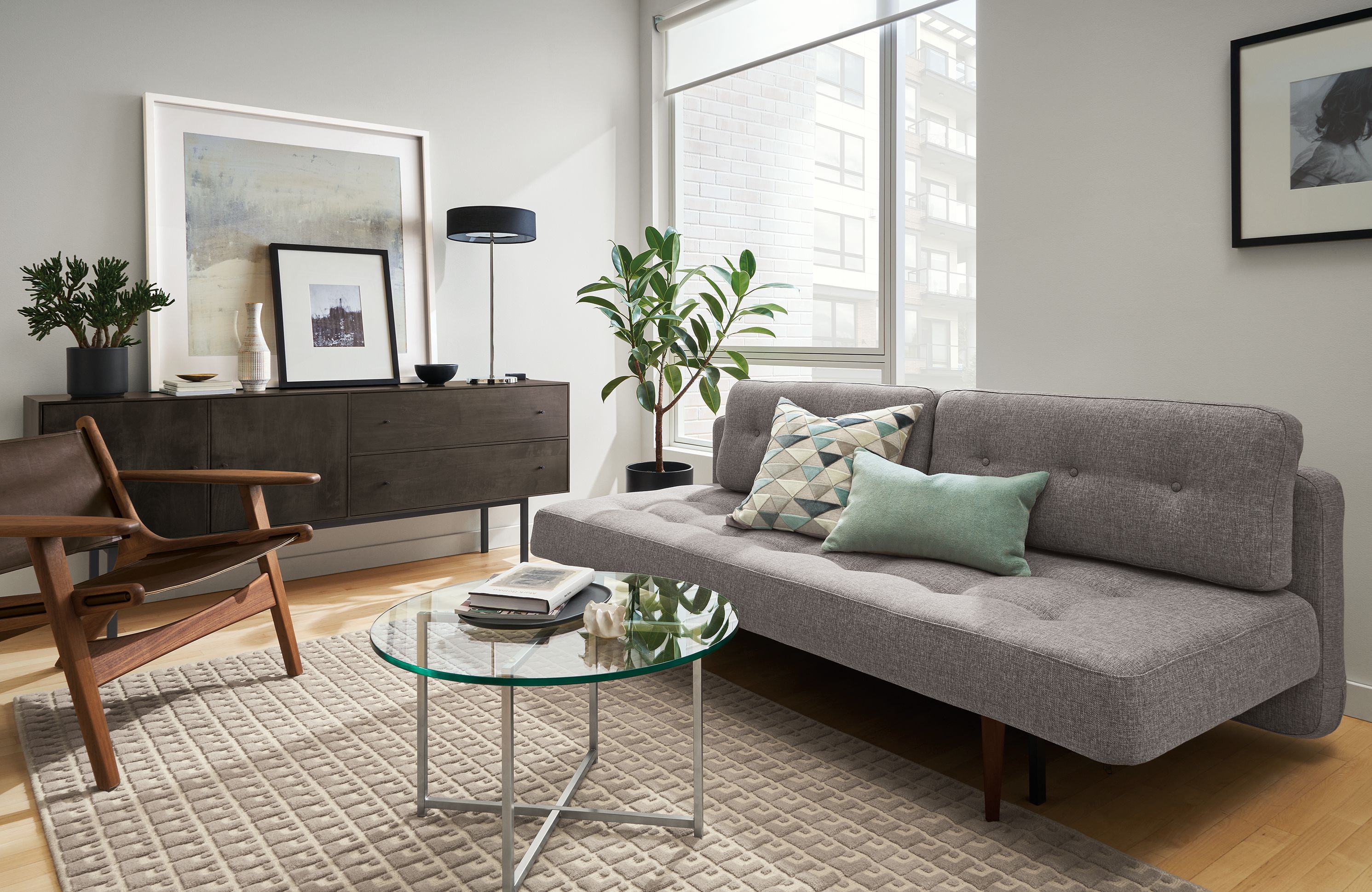 Living room with Deco 79-wide sleeper sofa in Ula Grey, Lars lounge chair in Sellare Smoke and Modo rug in Cement.