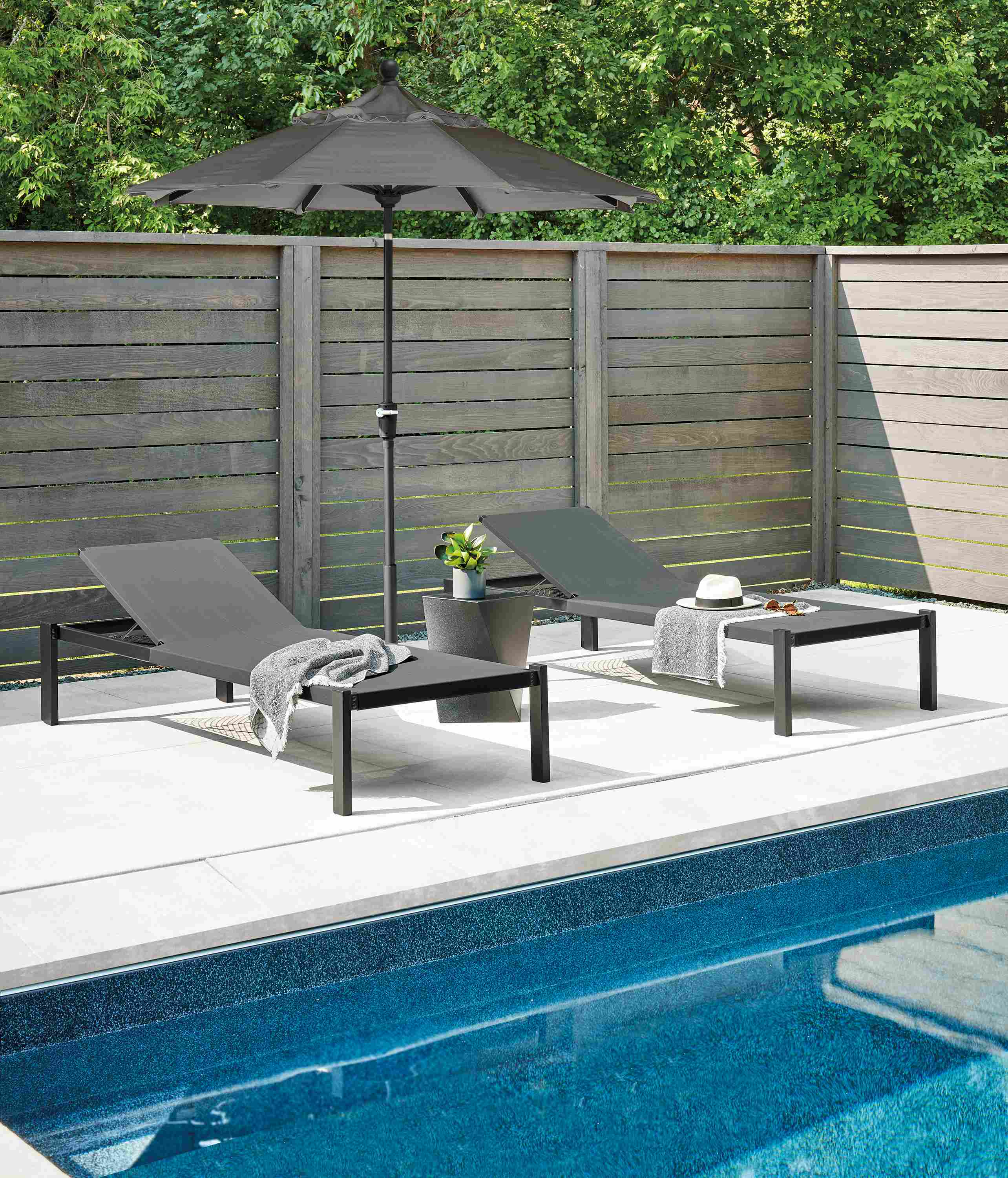 Pool area with Dorian chaise in black and kubik square stool in black and maui patio umbrella in tavros charcoal.