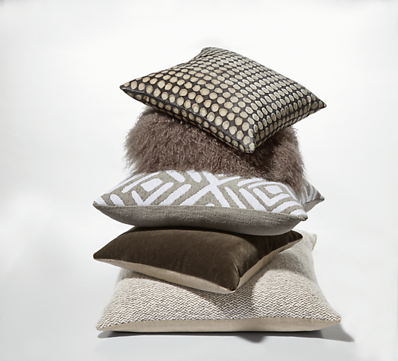 Stack of throw pillows in various textures in ivory and greys.