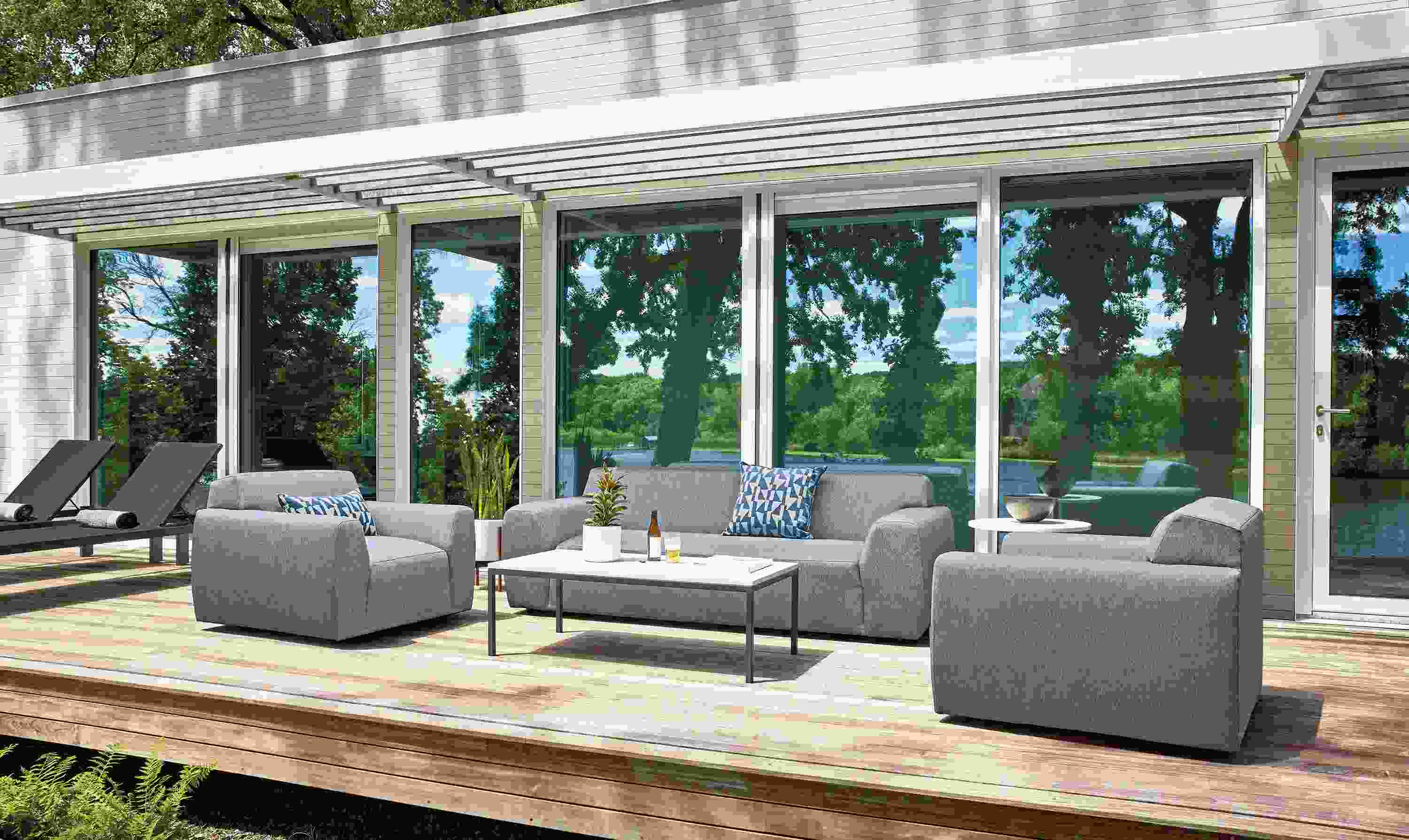 Deck with Drift sofa and 2 Drift swivel chairs in Mist Navy and Aria outdoor side table graphite with white quartz top.