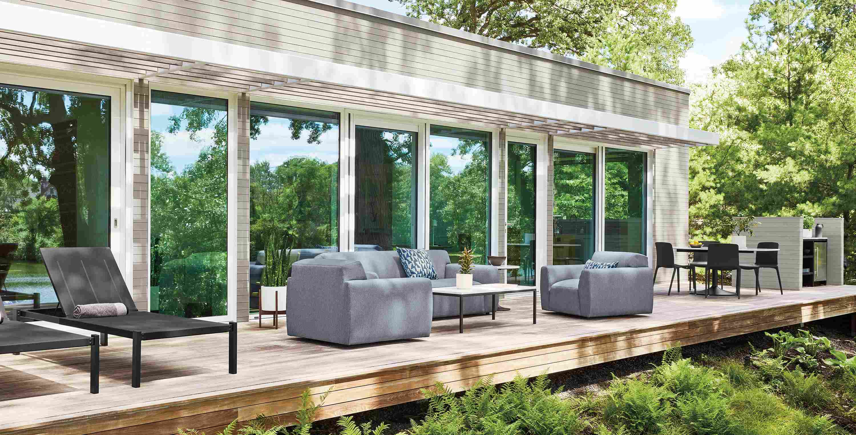 Large home deck with Drift sofa and 2 Drift swivel chairs in Mist Navy, 2 Dorian chaises and Aria side table.