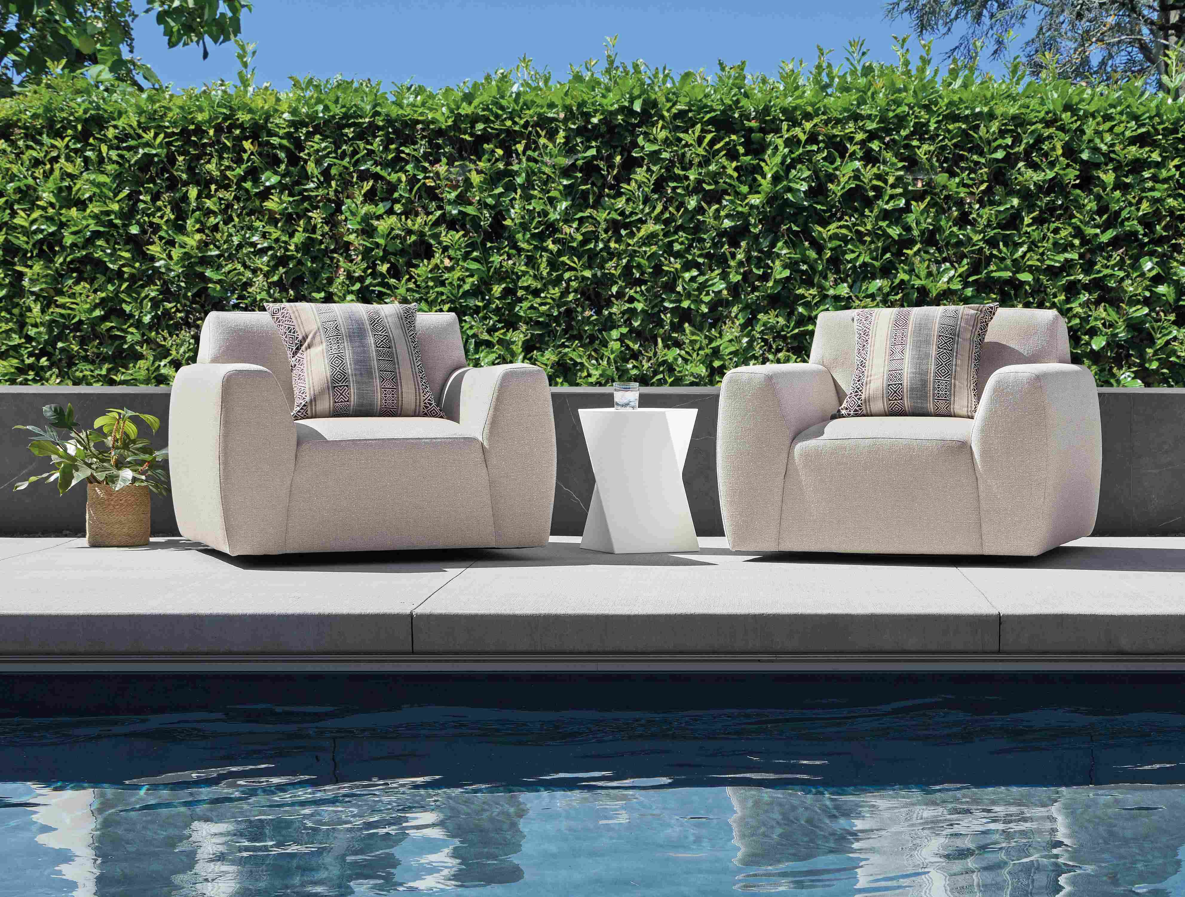 Pool area with 2 drift swivel chairs in nevan grey, kubik square table/stool in white and yates outdoor pillow in otter.
