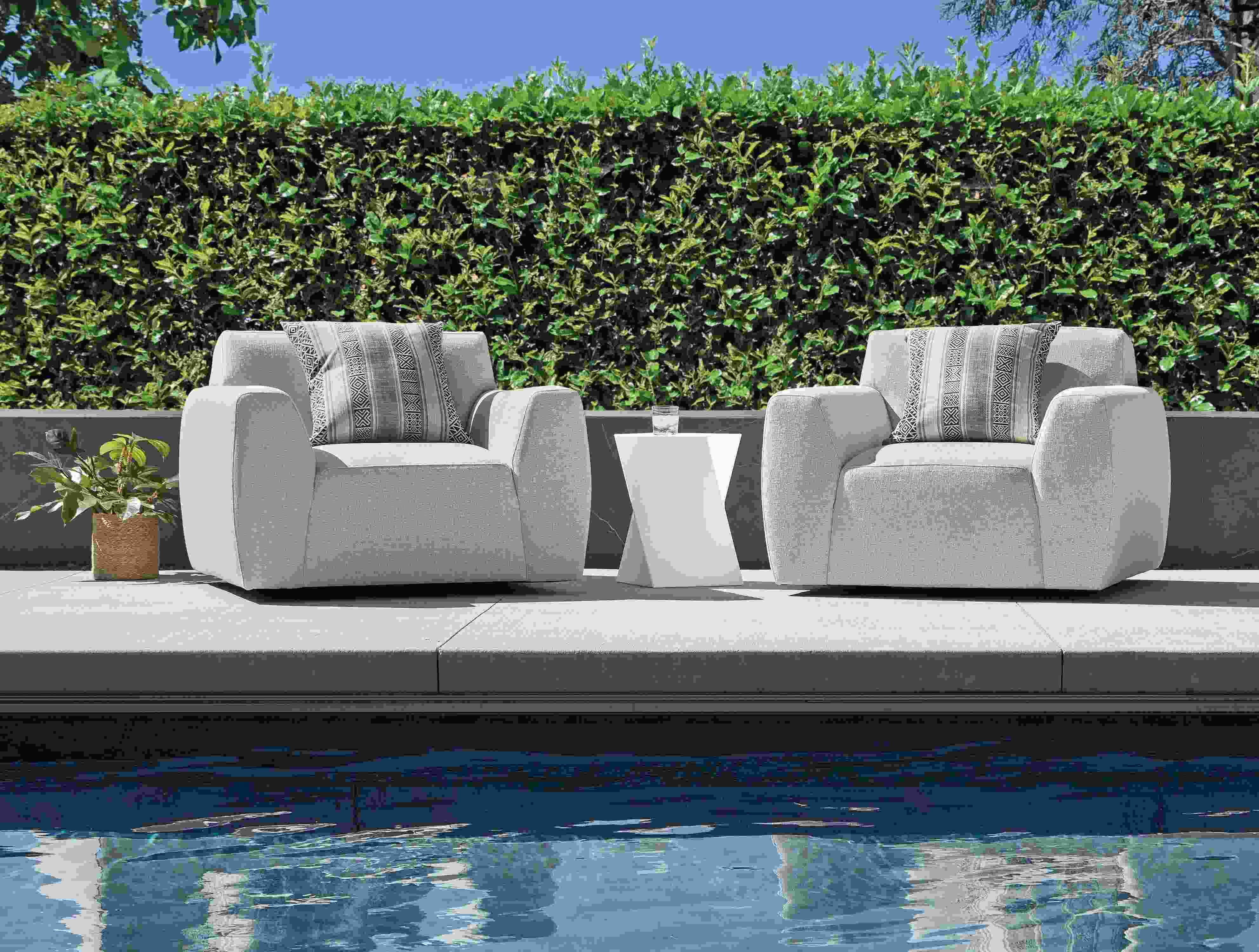 Pool area with 2 drift swivel chairs in nevan grey, kubik square table/stool in white and yates outdoor pillow in otter.