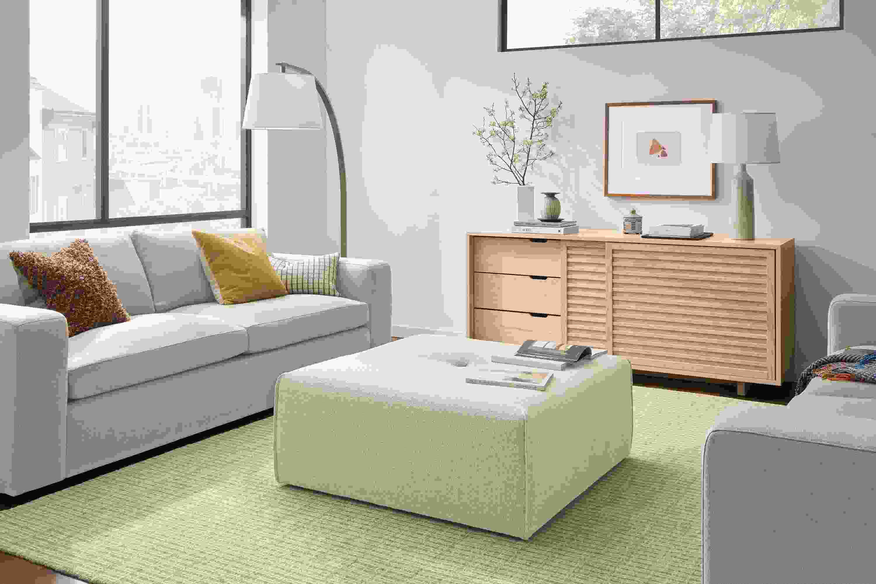 Living room with Dupree ottoman in Conley Natural and 2 Baylor sofas in Landen Asphalt.