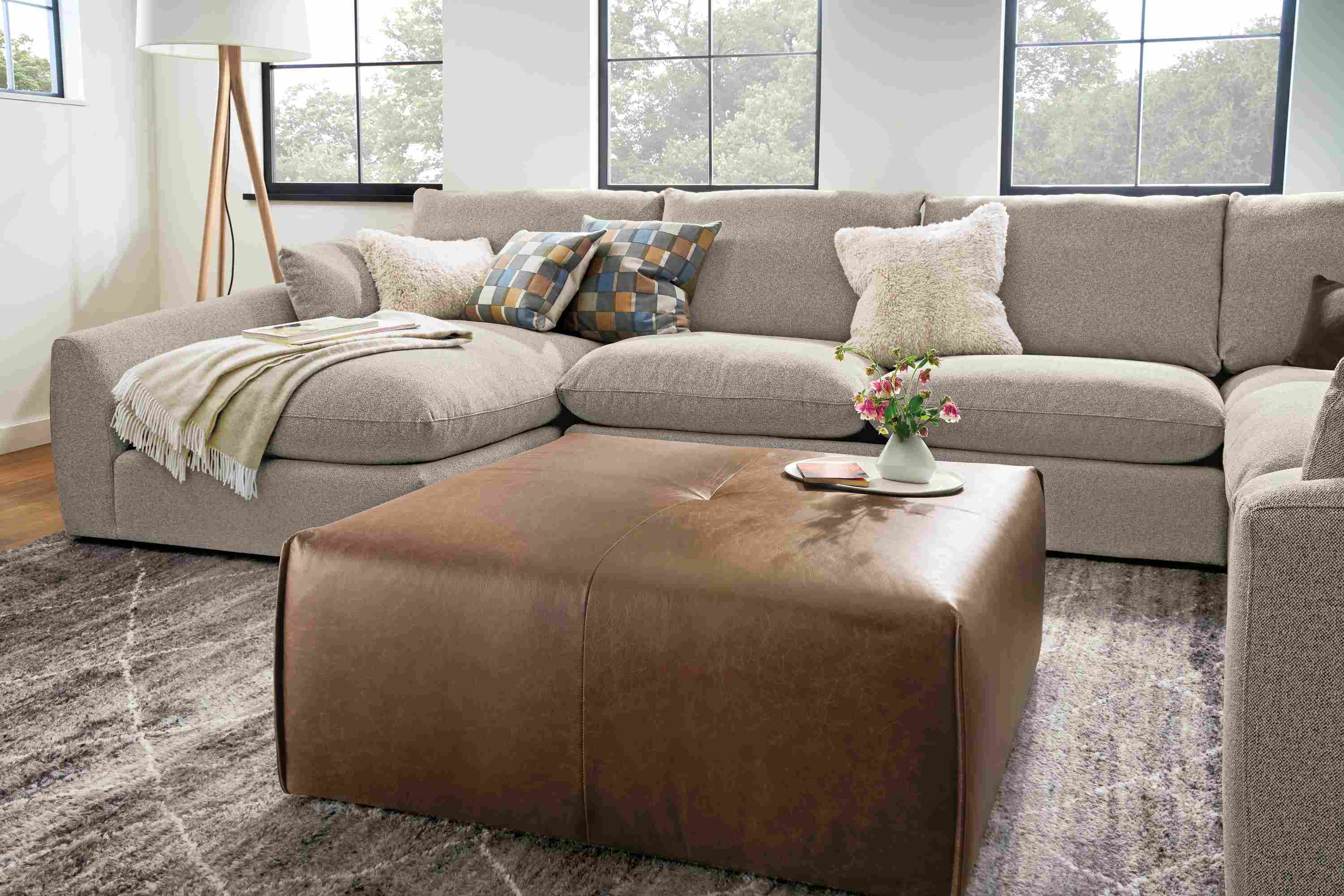 Living room with Dupree ottoman in Palermo Bourbon, Weber sectional sofa in Tatum Bone and Kalindi rug in charcoal.