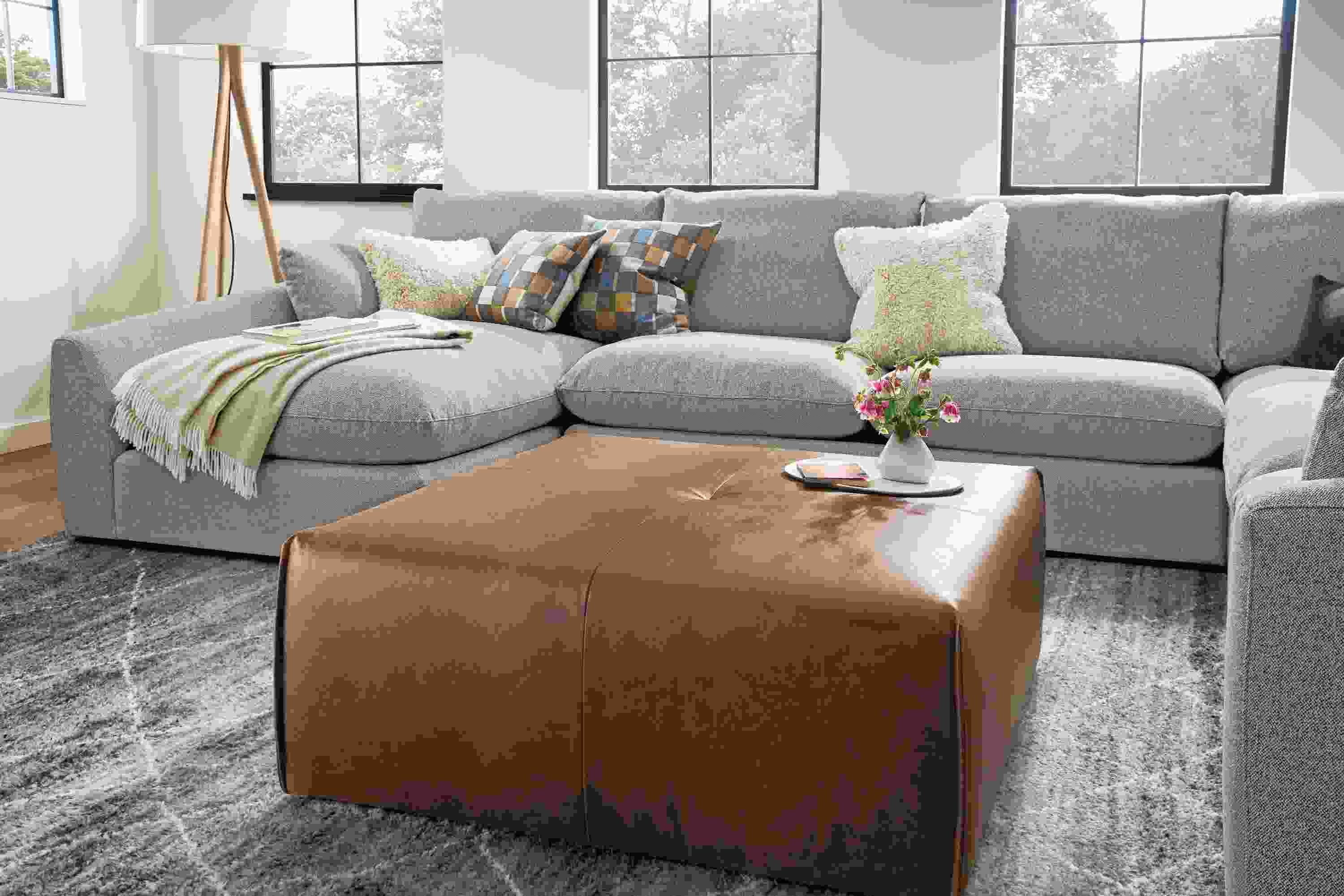 Living room with Dupree ottoman in Palermo Bourbon, Weber sectional sofa in Tatum Bone and Kalindi rug in charcoal.