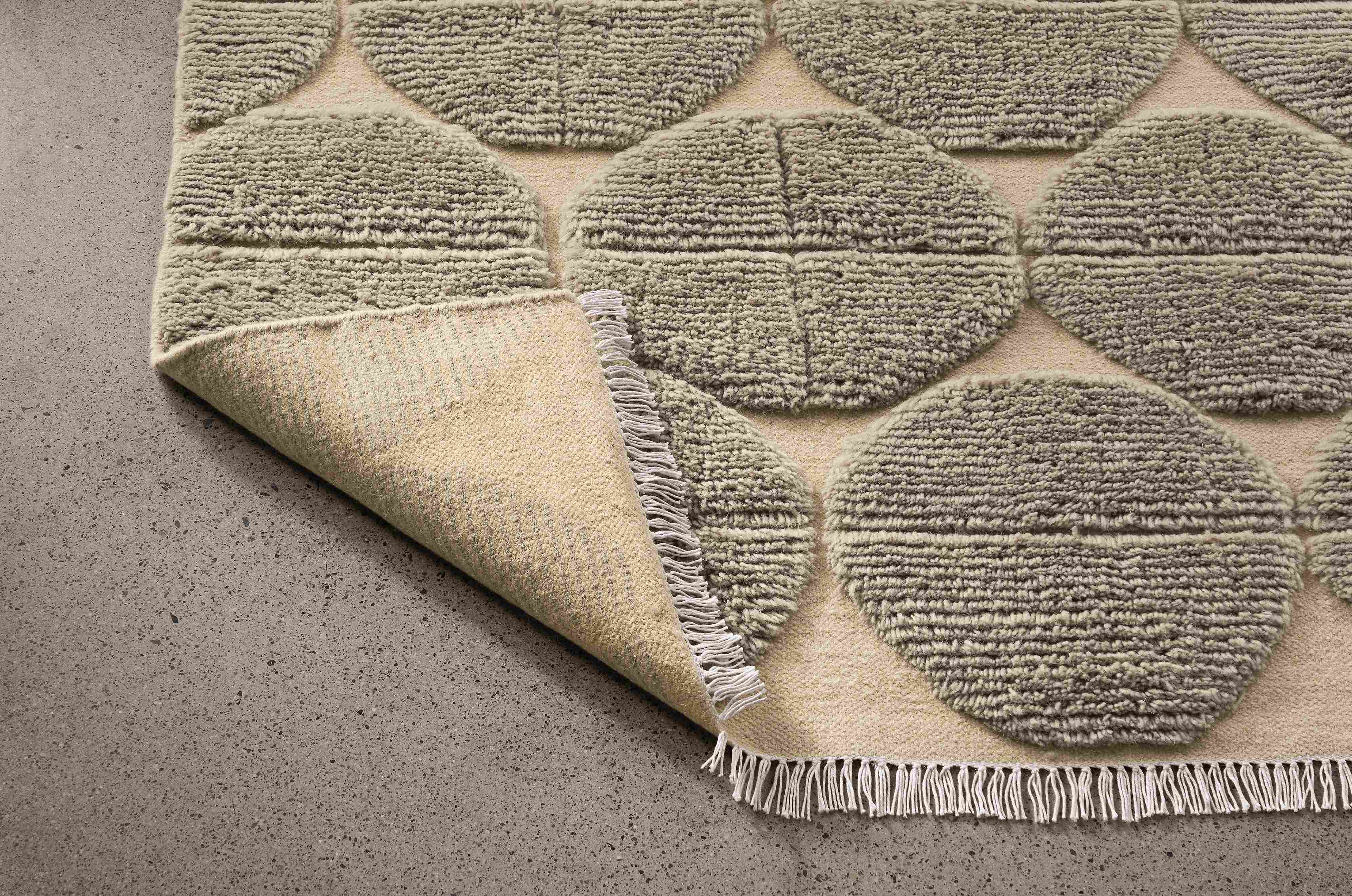 Detail of Edo 8 by 10 rug in asphalt shown with corner flipped up to show underside of rug.