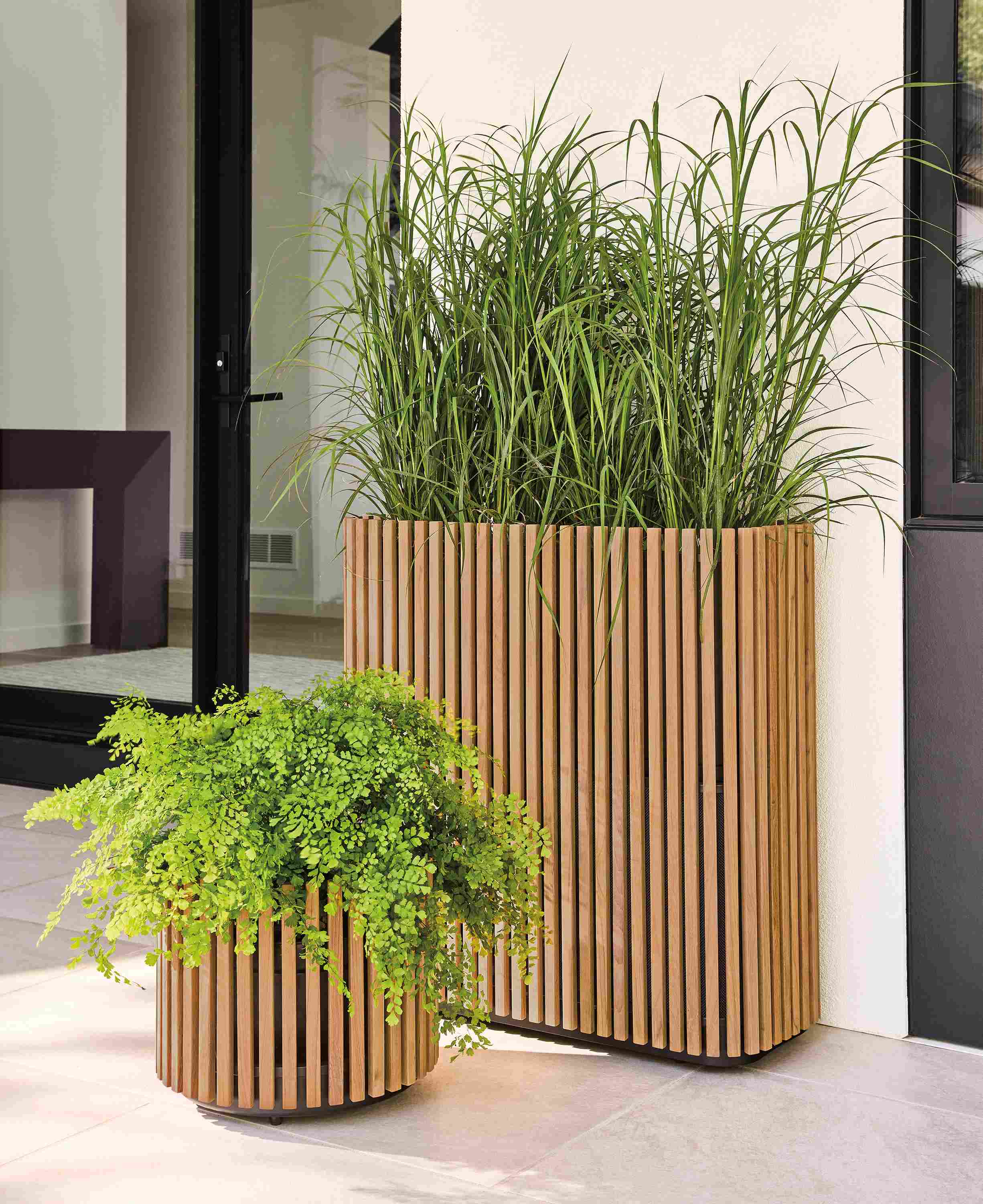 Elba 17-diameter round planter and 32-wide rectangular planter in teak heartwood on a home patio.
