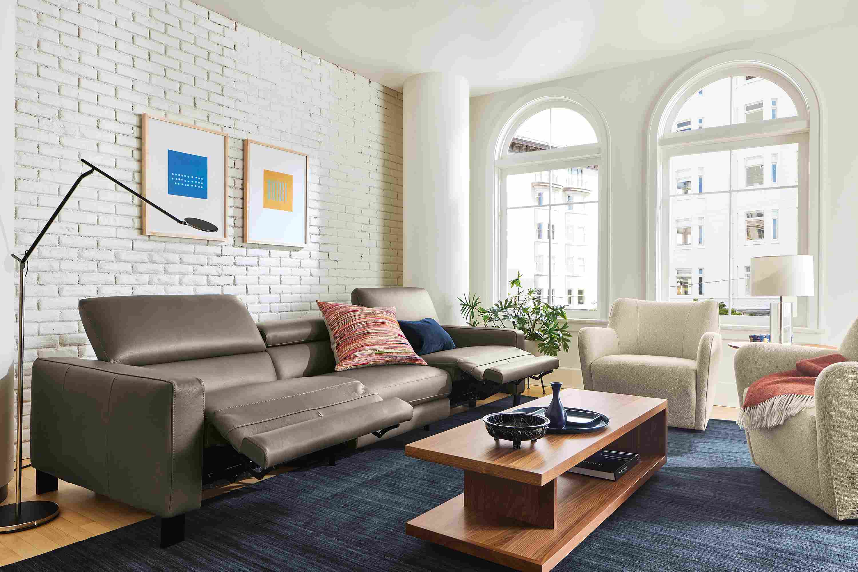 Living room with Elio sectional in dario smoke leather shown with two seats in reclining position.