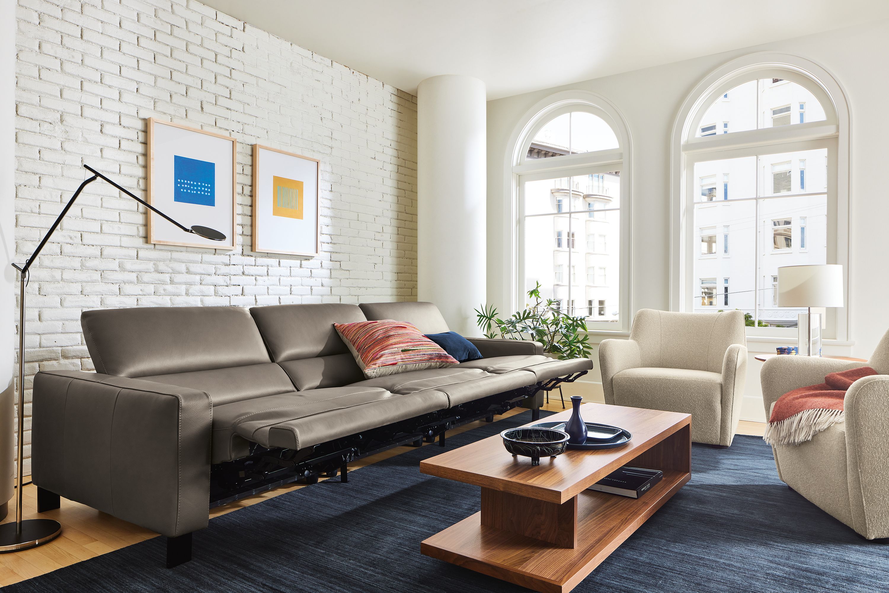 Living room with Elio sectional in dario smoke leather shown with all seats in reclining position.