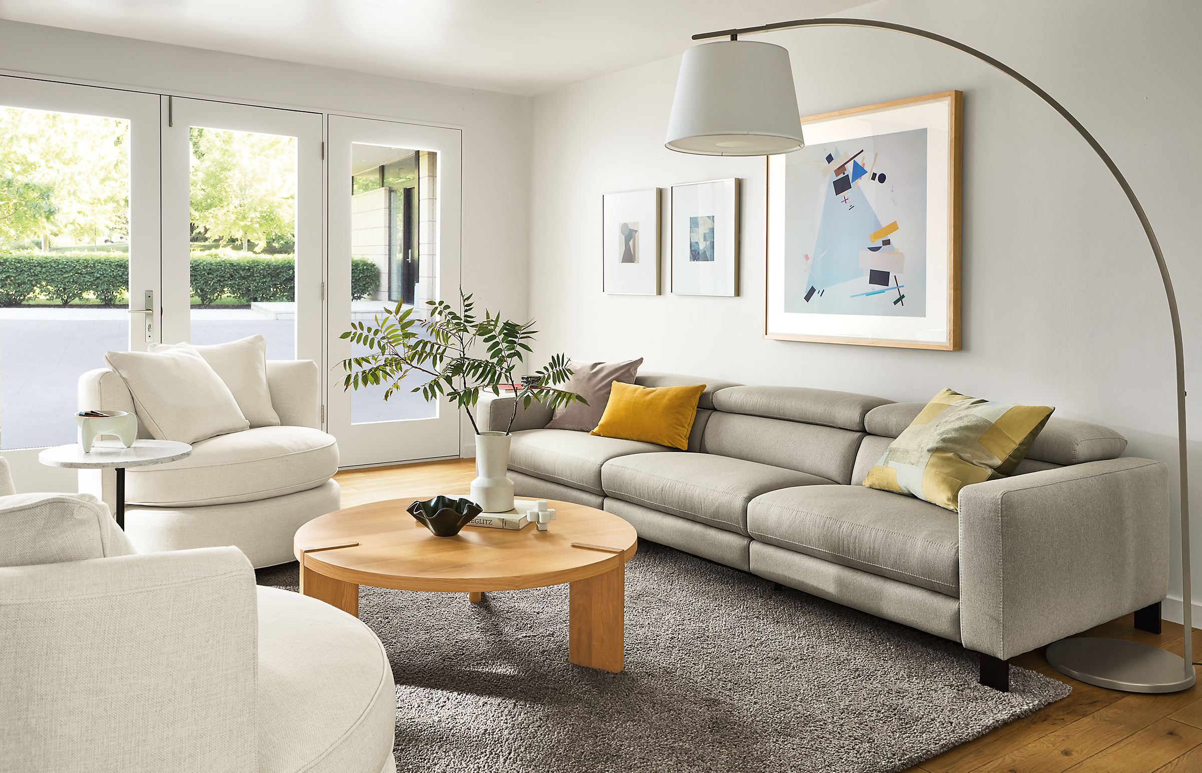 living room with elio sofa in sussex cement fabric with eos swivel chairs in ivory and hanover coffee table in white oak.