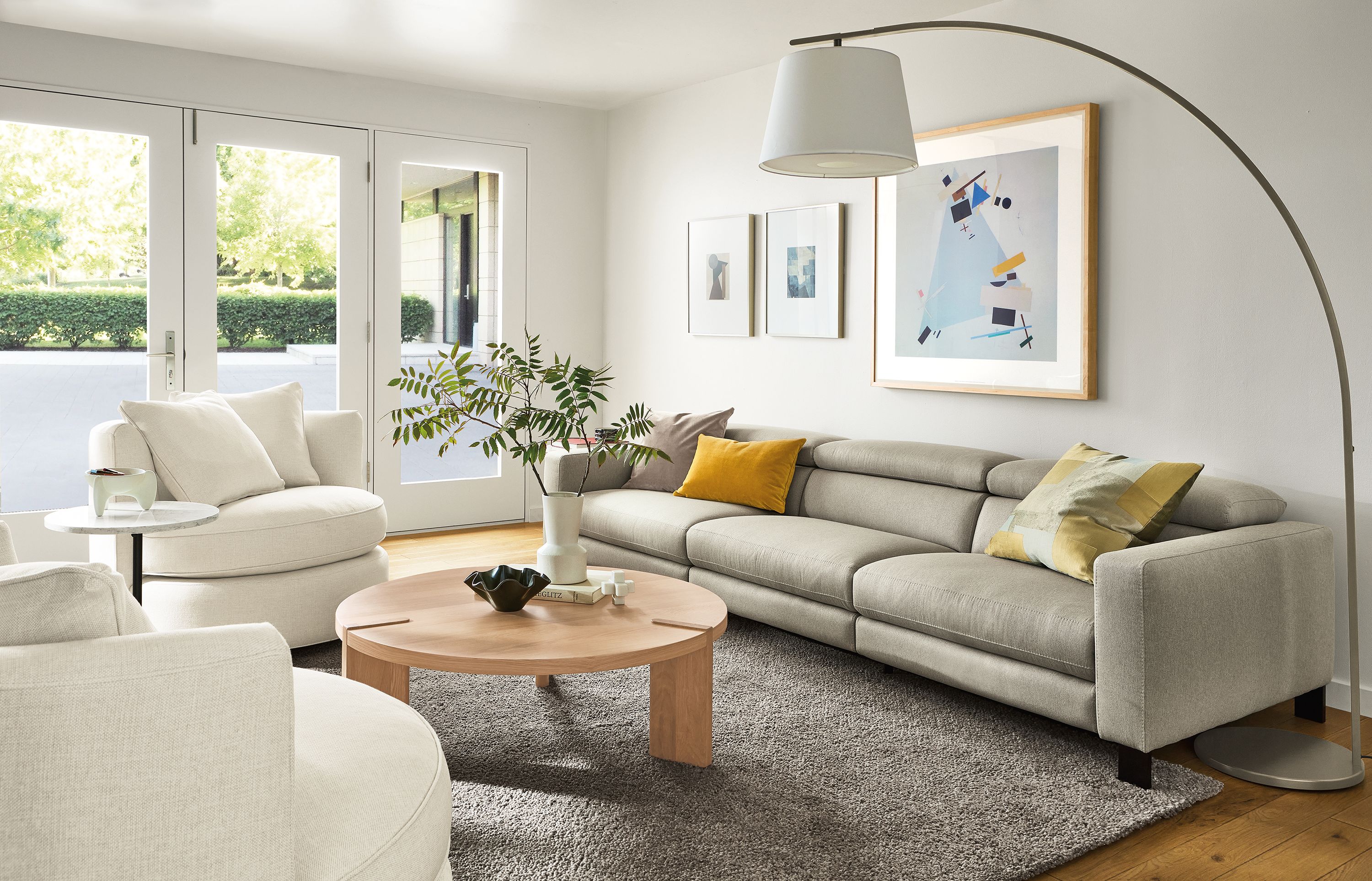 Living room with elio sofa in sussex cement, eos swivel chairs in sumner ivory and Hanover coffee table in rye on red oak.