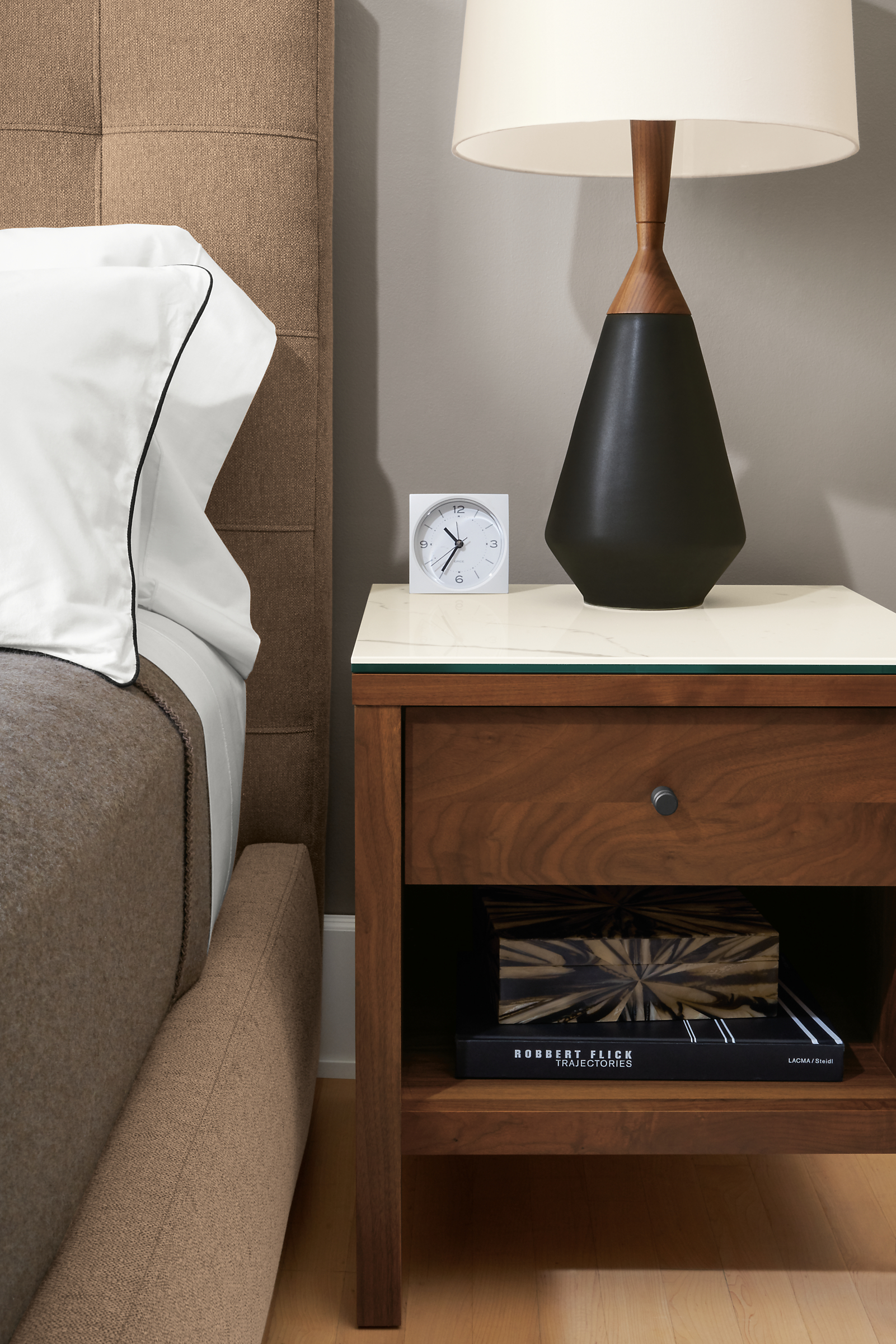 Detail of Emerson nightstand in walnut with white ceramic top in bedroom.